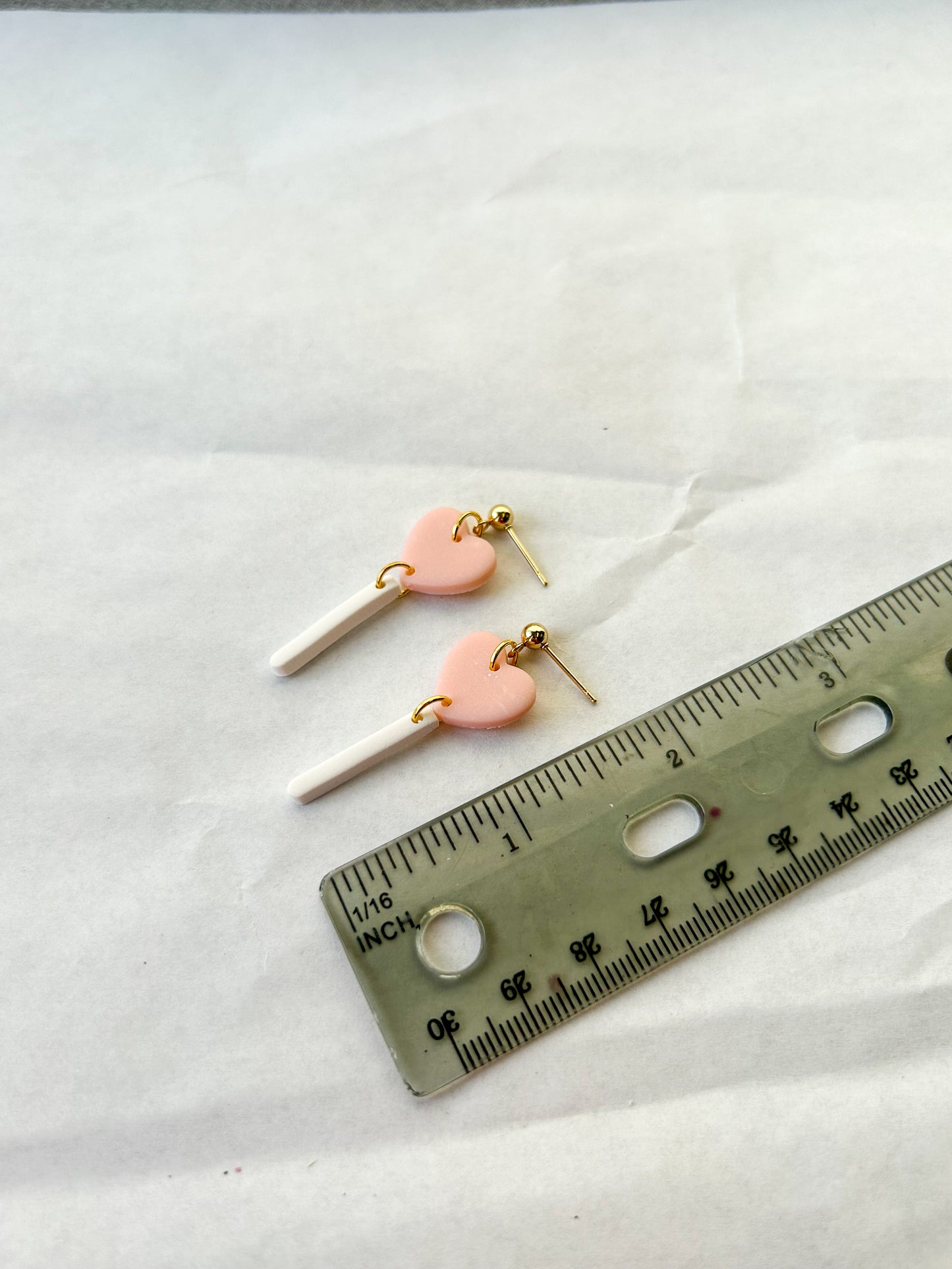 Heart-shaped earrings next to a ruler on a white background
2 inches in length
