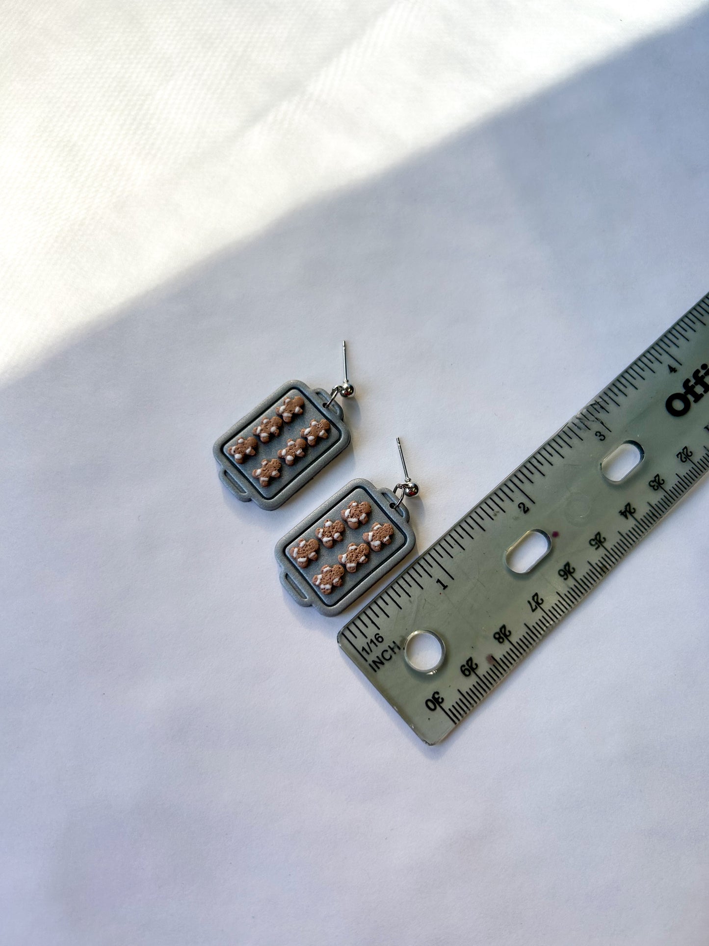 Pair of earrings next to a ruler on a white background