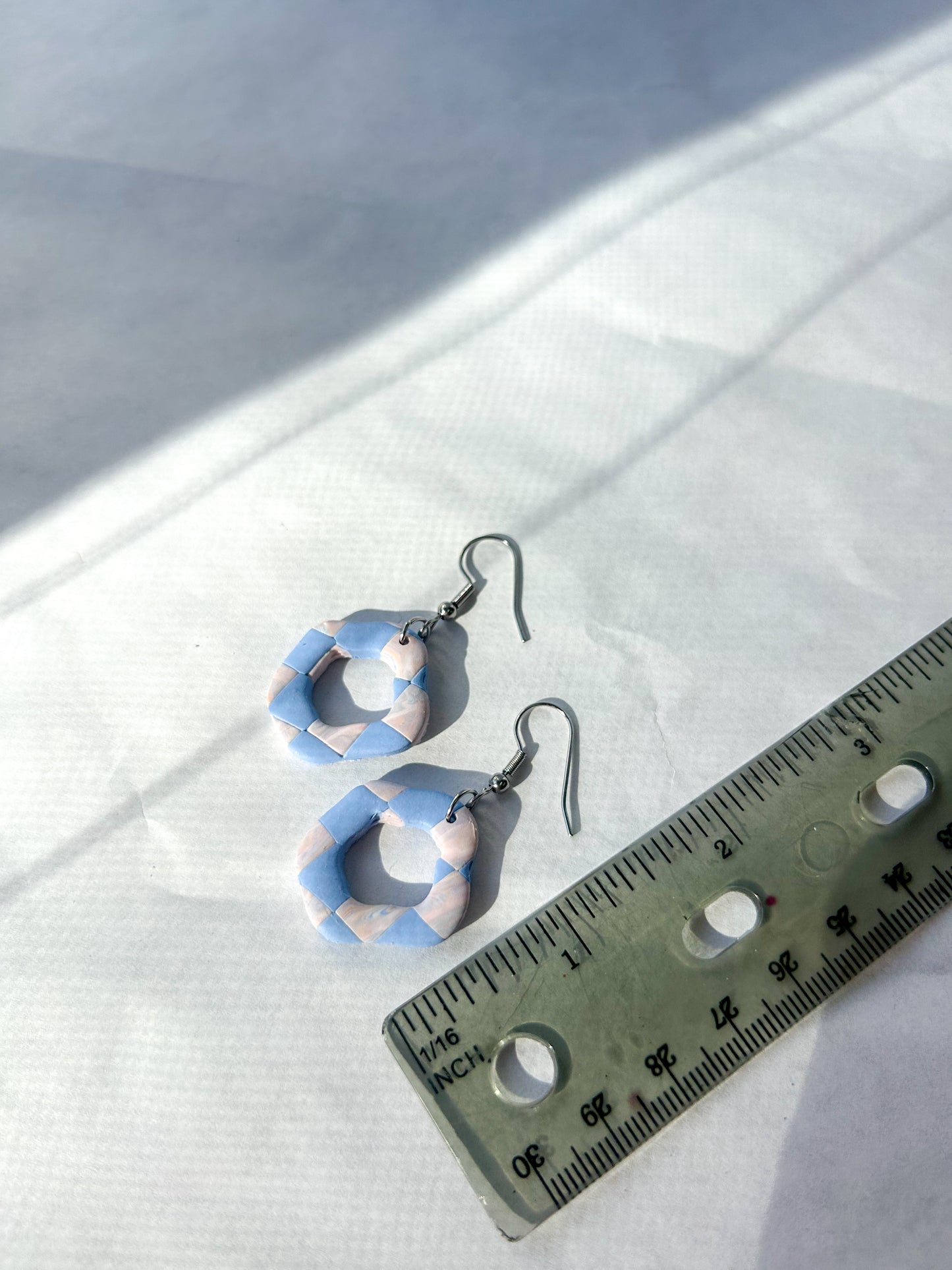 Earrings laying on a flat surface to show that they are one and a half inches long