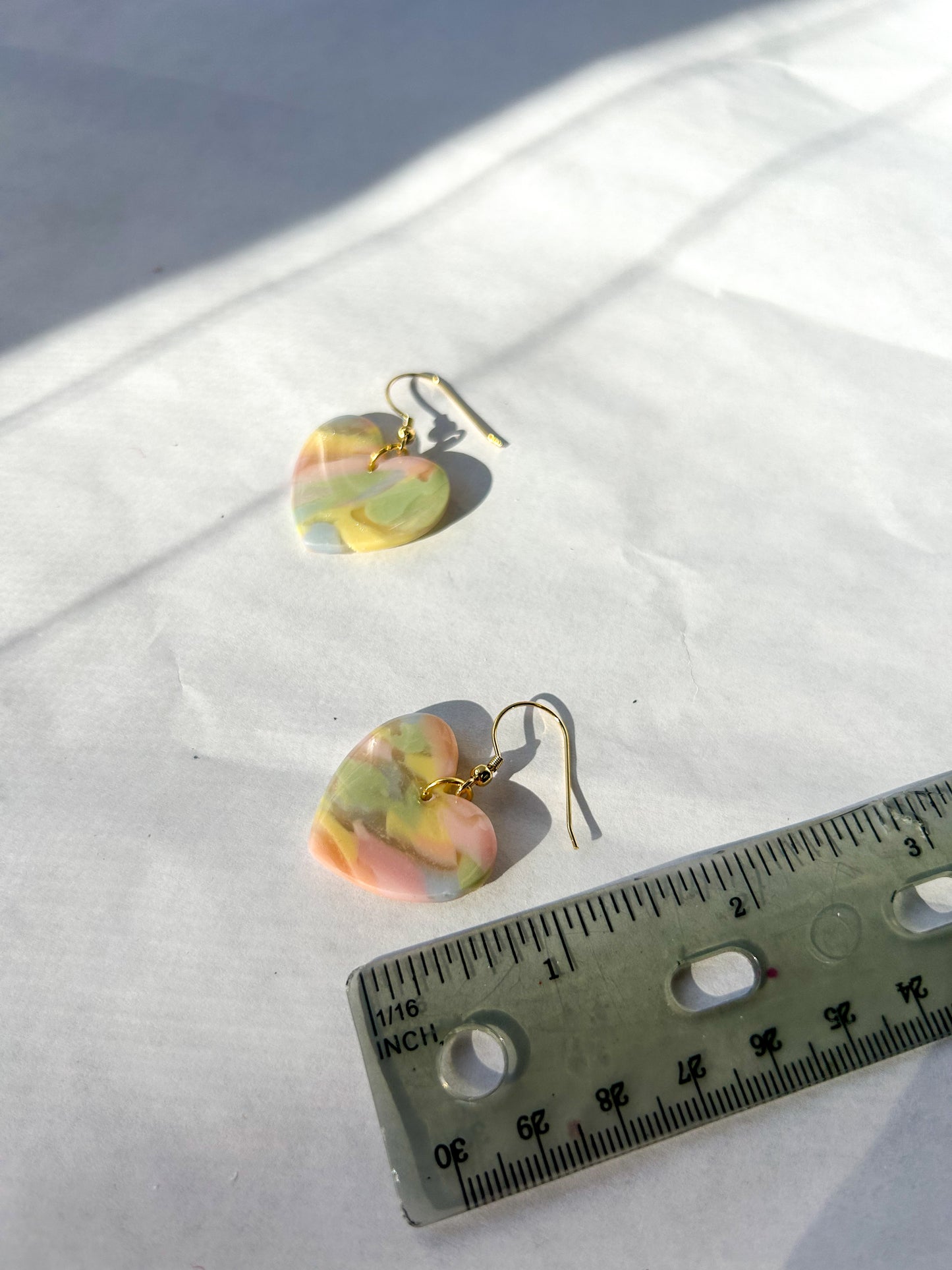 Heart shaped earrings next to a ruler for skill to show that they are 1 1/2 inches long