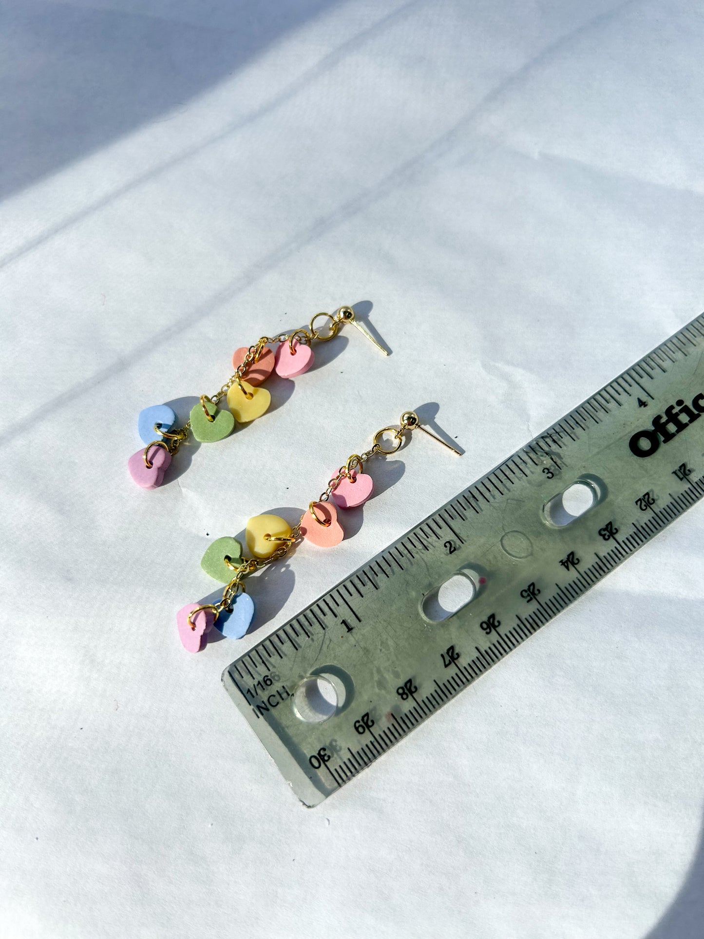 Colorful beaded earrings next to a ruler on a white background. 2.5 inches in length