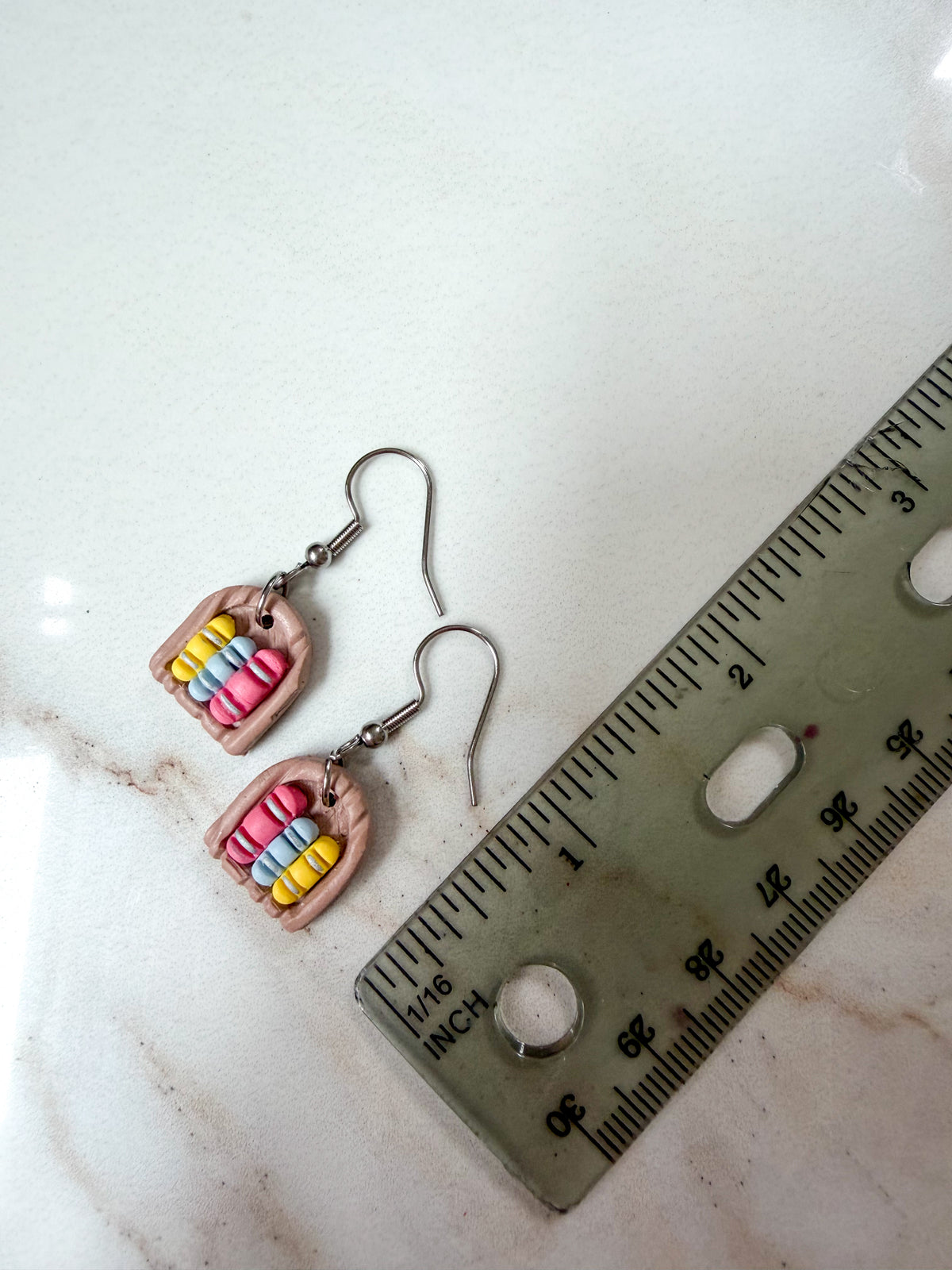 Earrings lying next to a ruler for scale. About 1 1/2 inches in length.