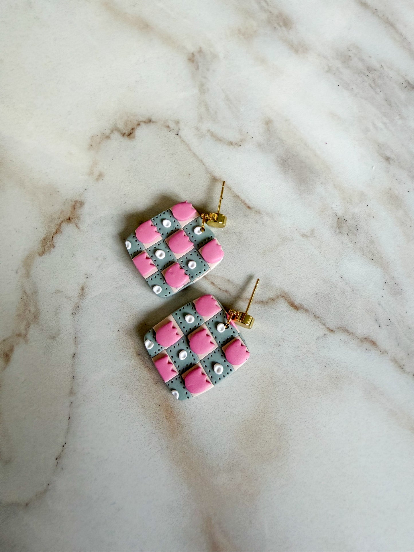 Pair of earrings with pink and gray pattern on a marble surface