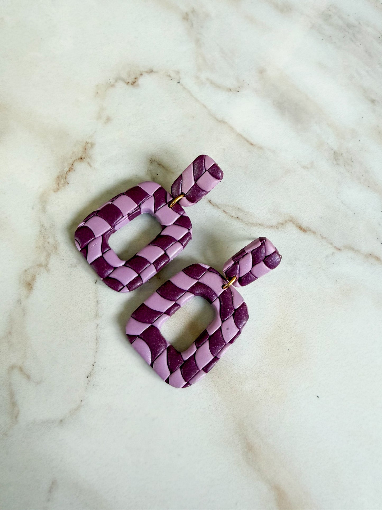 Purple checker earrings on a marble surface. 