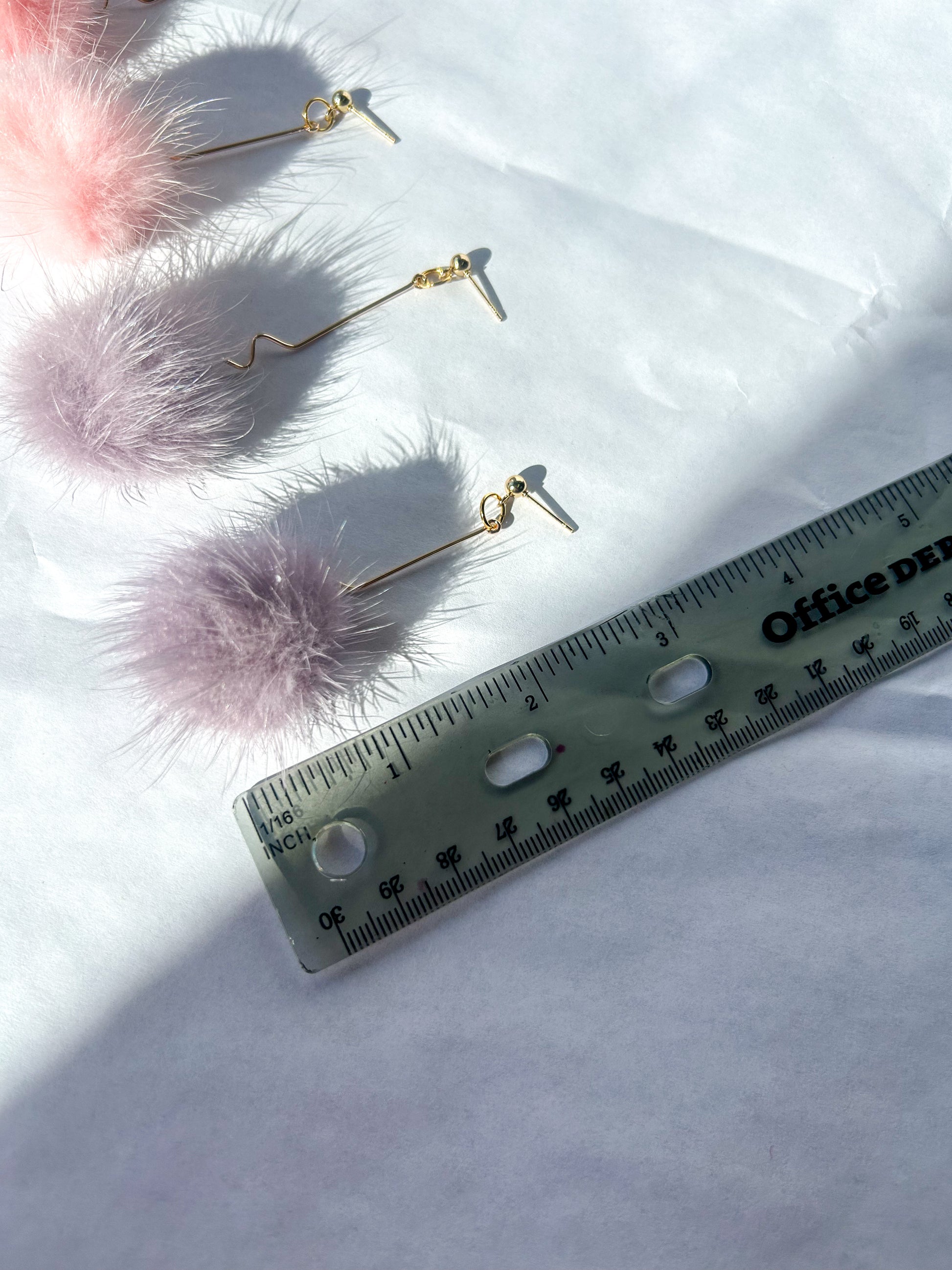 Pink fluffy earrings with gold hooks on a white surface next to a ruler for scale. 3 inches in length 