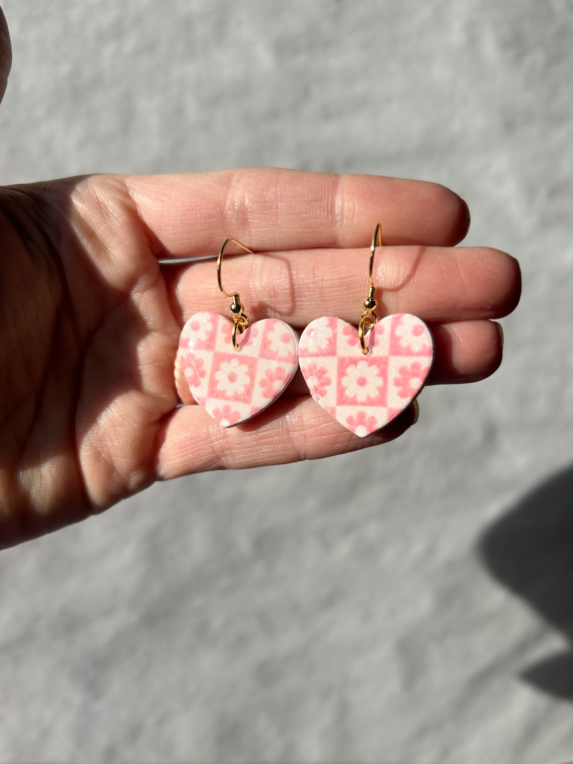 Hand holding a pair of earrings with a checker pattern