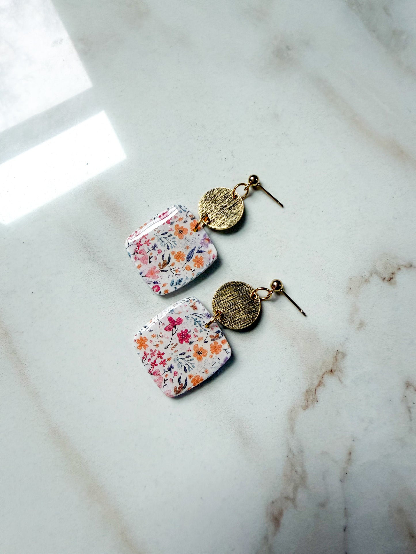 Floral earrings with gold accents on a marble surface