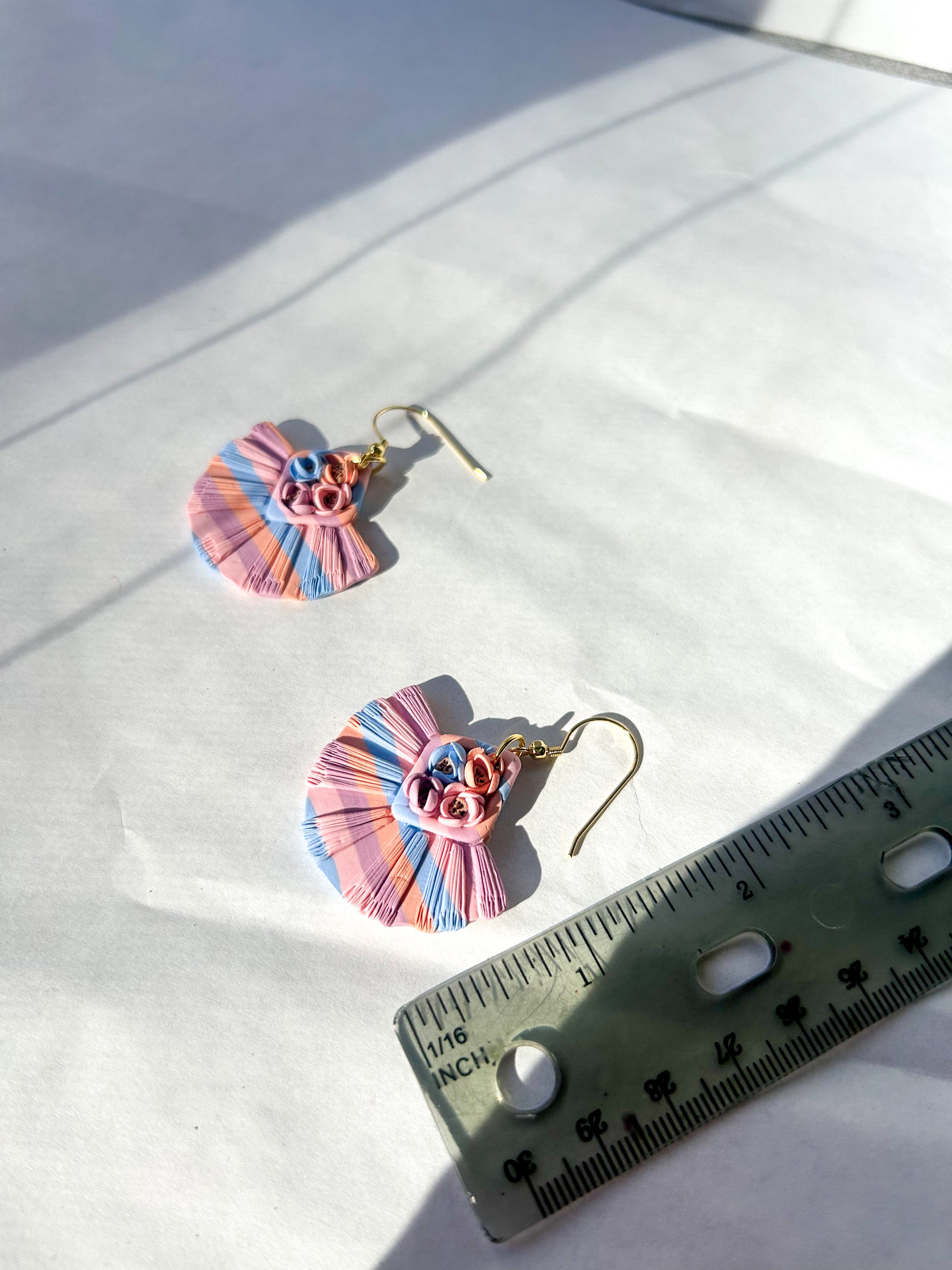 Colorful ruffled earrings on a white fabric background with a ruler for scale. About 2 inches in length