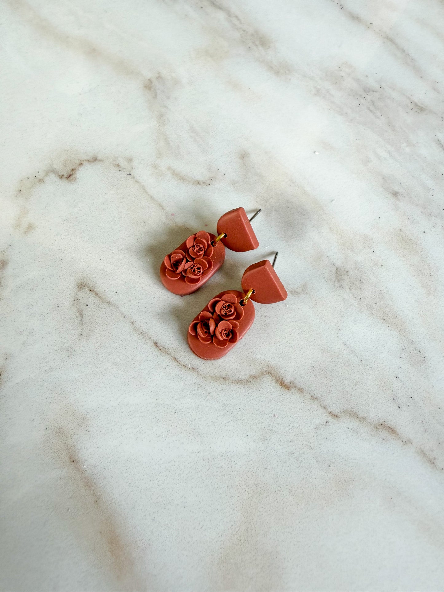 Pair of red floral earrings on a marble surface