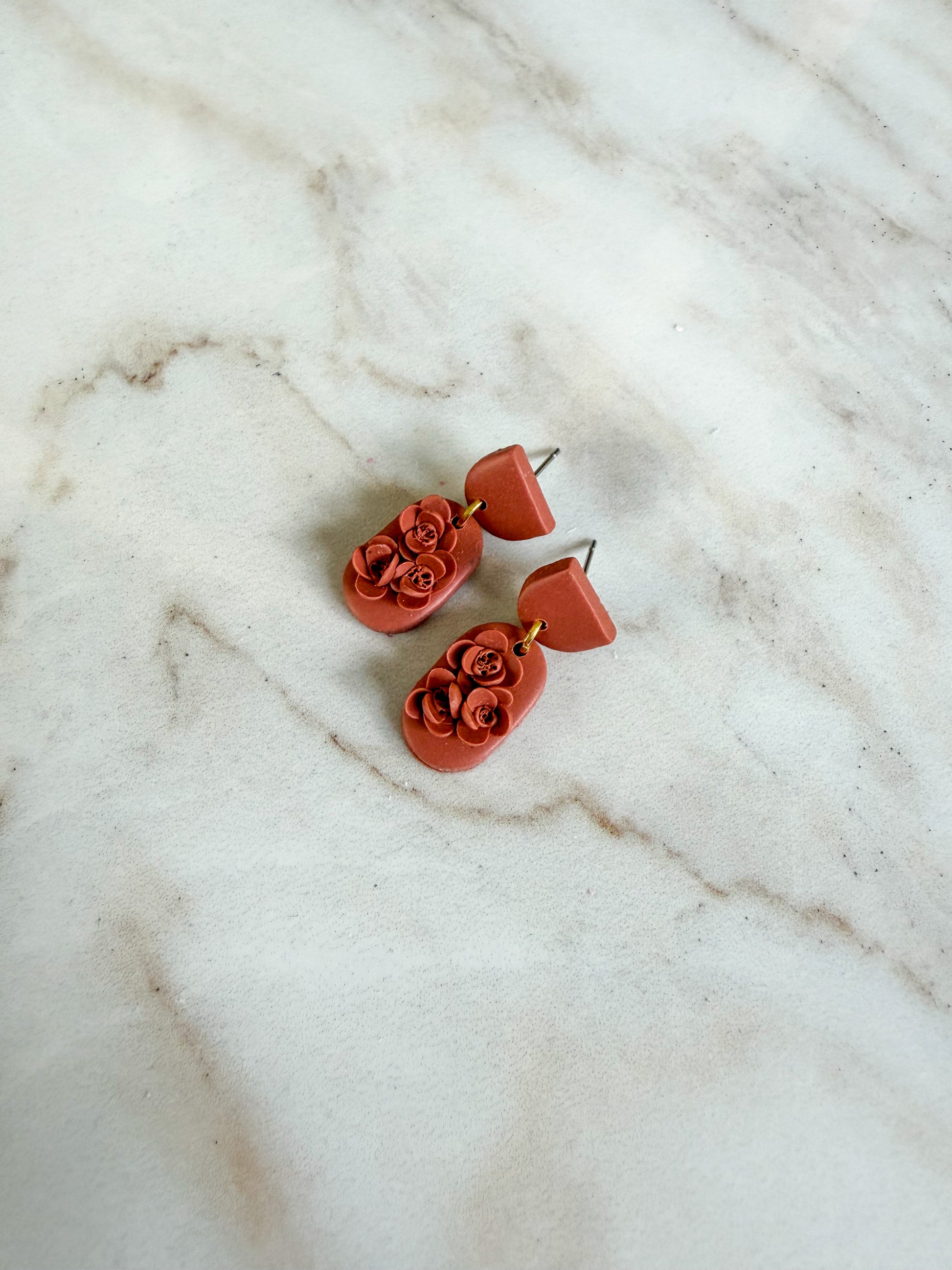 Pair of red floral earrings on a marble surface
