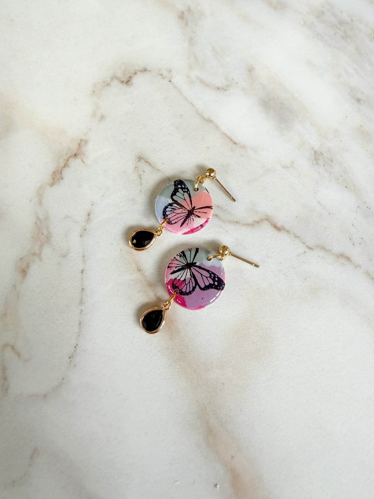 Butterfly-themed earrings on a marble surface