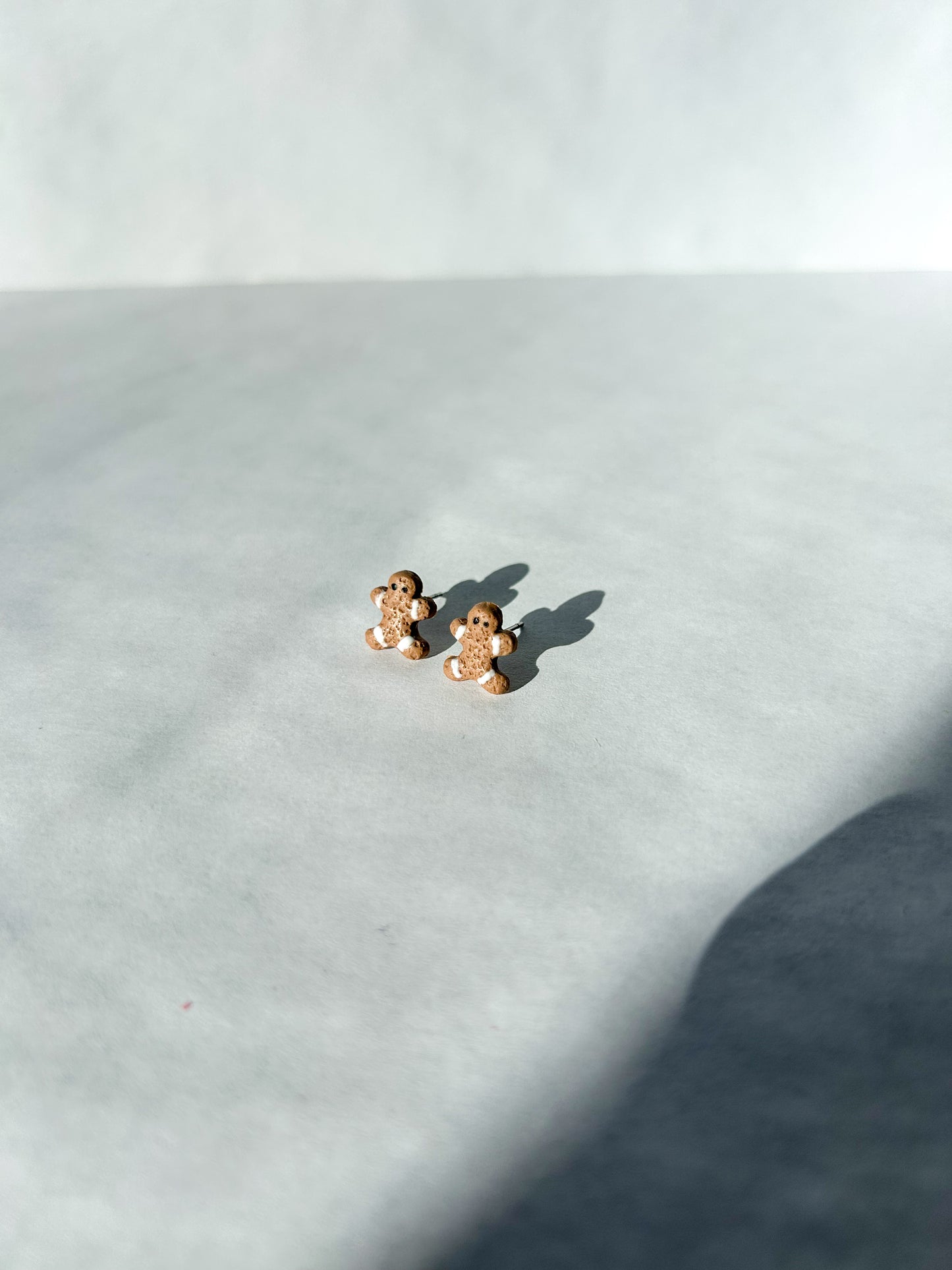 Small gingerbread man earrings on a light gray surface