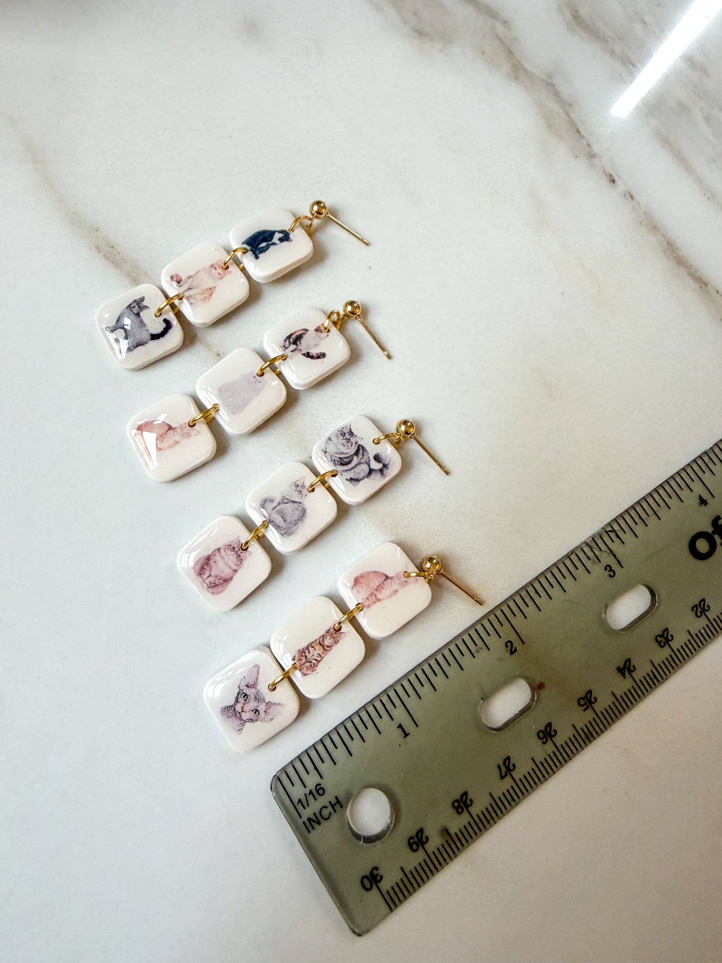 Four earrings laying next to a ruler for scale. 2 inches in length. 