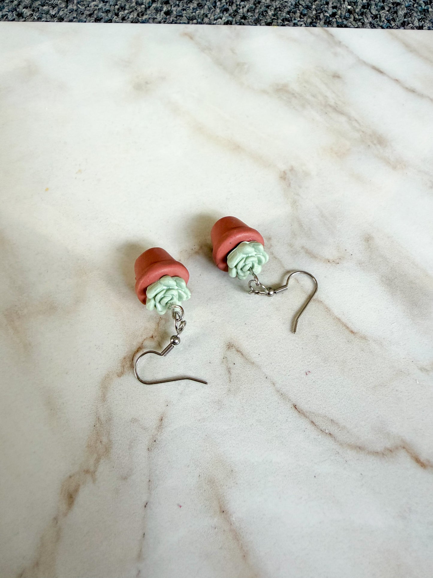 Potted plant-themed earrings on a marble surface