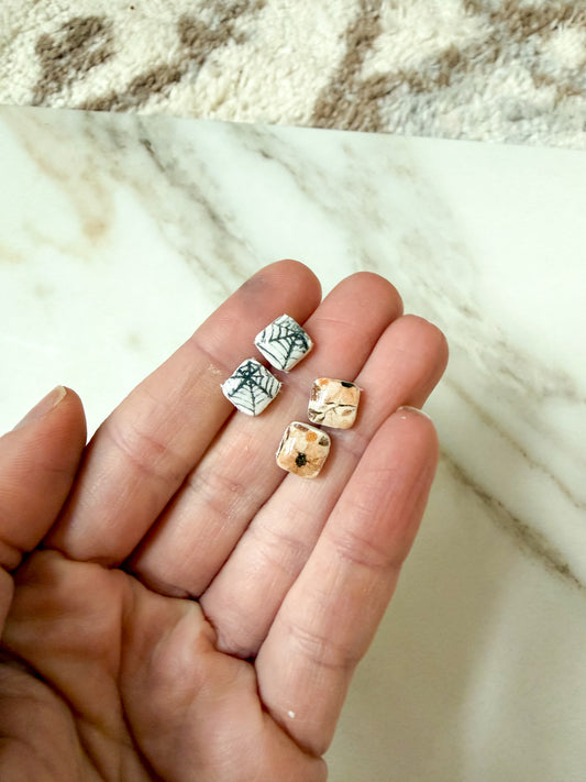 Hand holding two pairs of studs against a marble background 