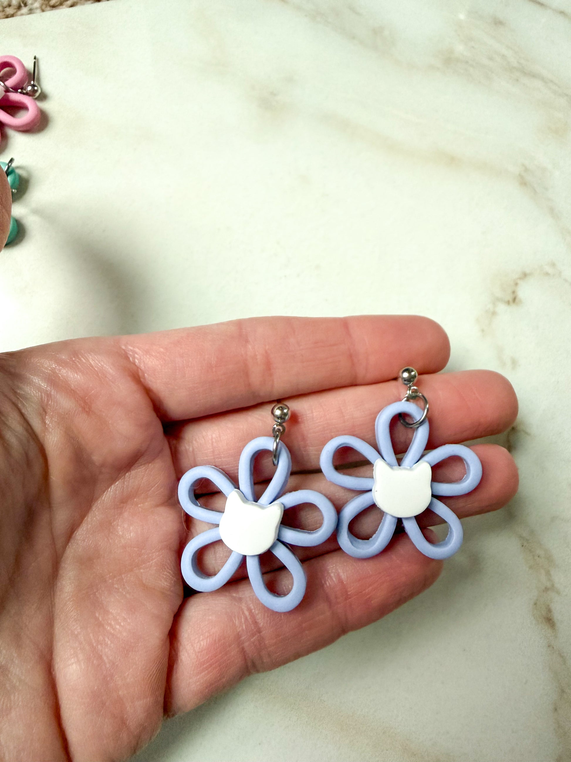 Periwinkle flower dangles with a white cat head in the center. 