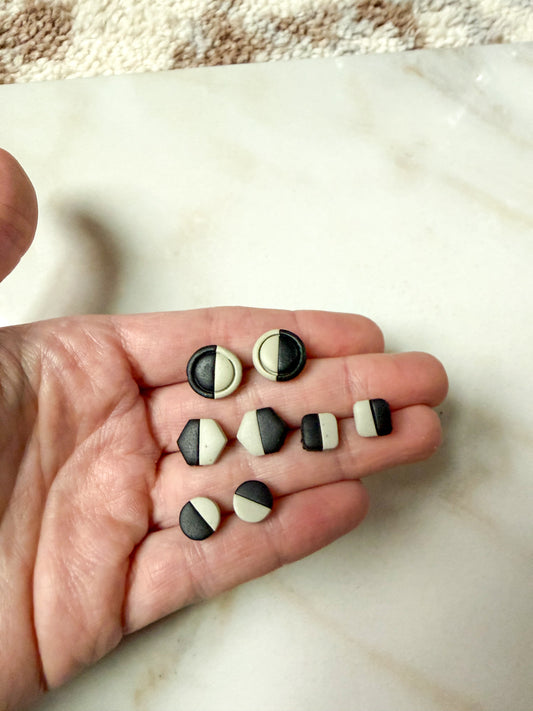 Hand holding black and green studs on a marble surface. 