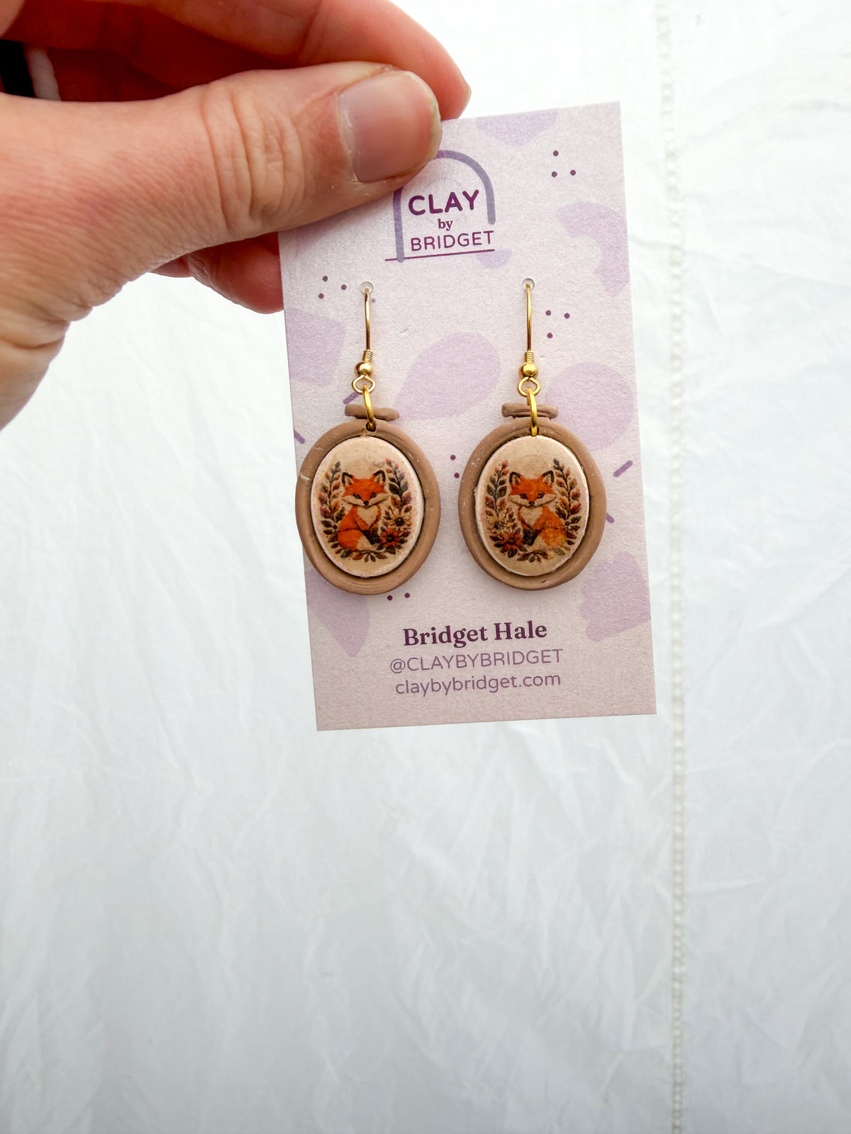 Embroidery hoop shaped earrings with a fox design inside.