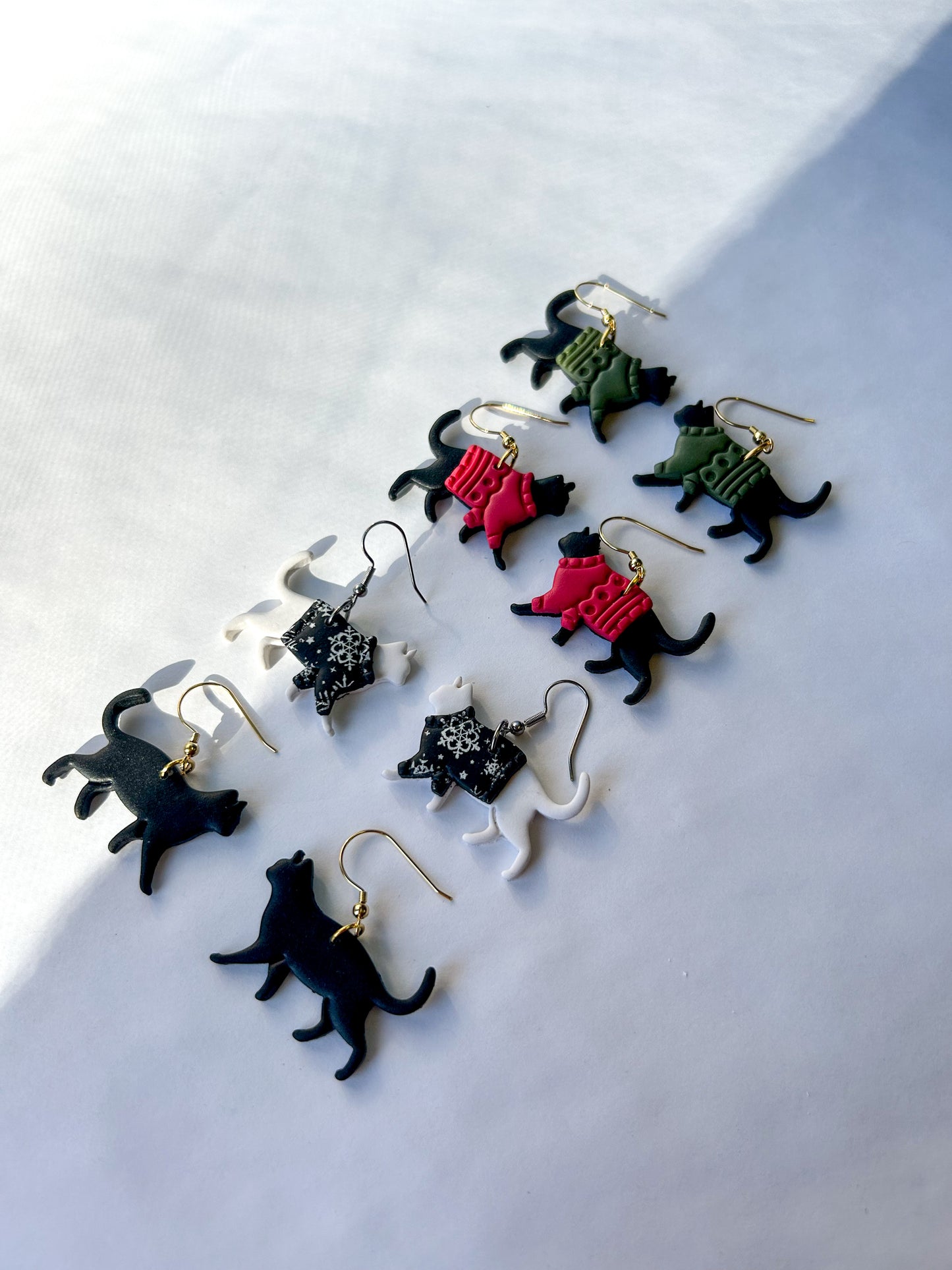 Collection of cat-shaped earrings on a white background. 
