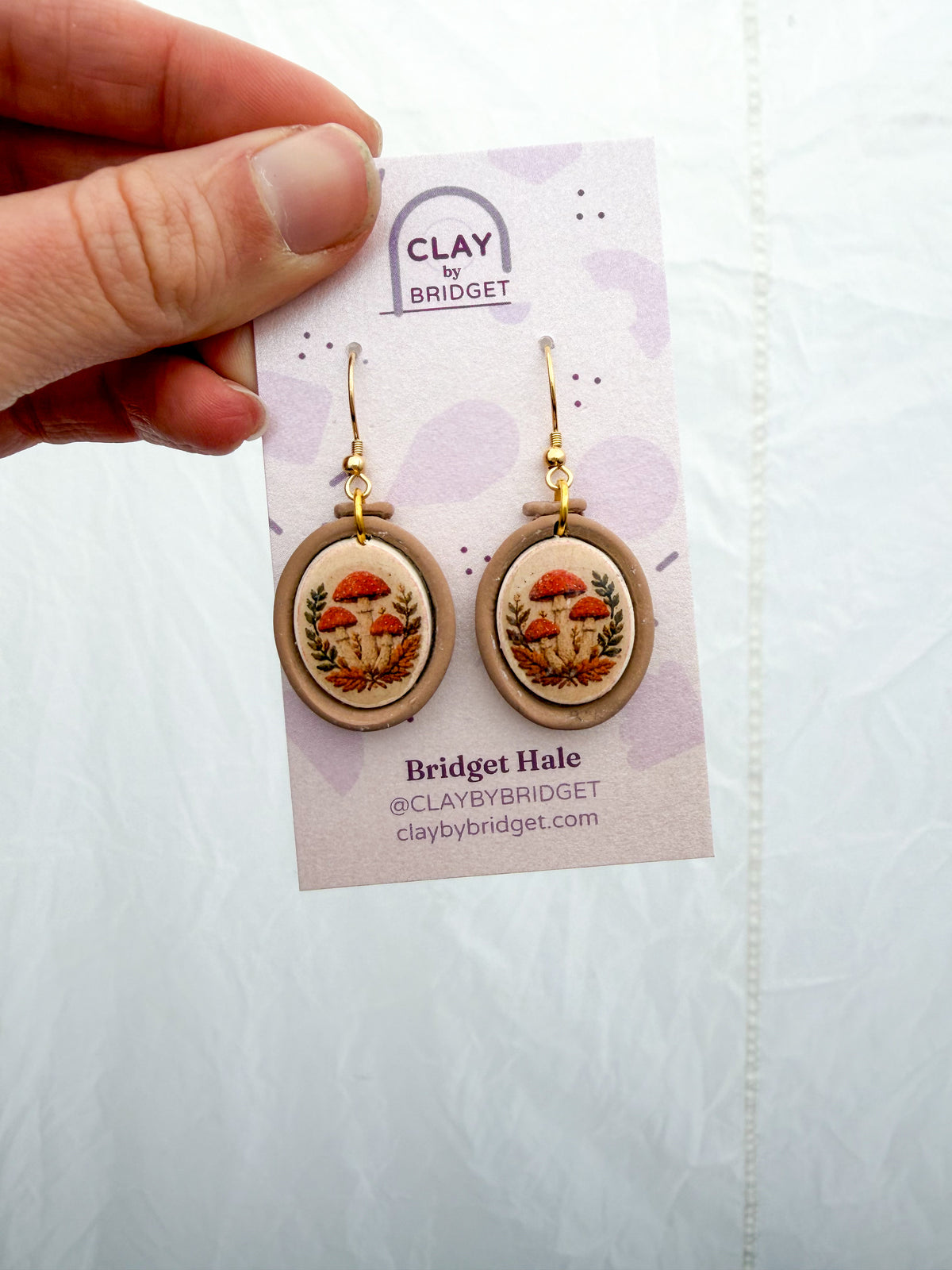 Embroidery hoop shaped earrings with a mushroom design inside.
