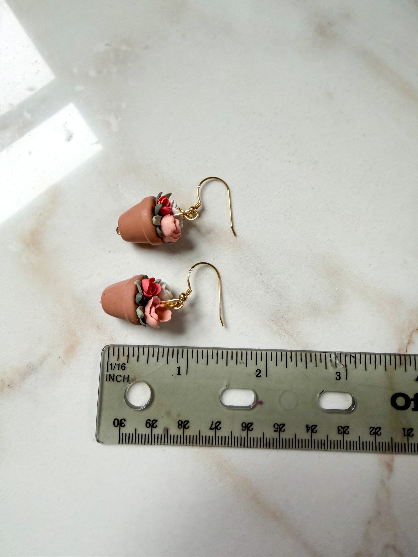 Pair of earrings on a marble surface with a ruler for scale. About 1.5 inches long. 