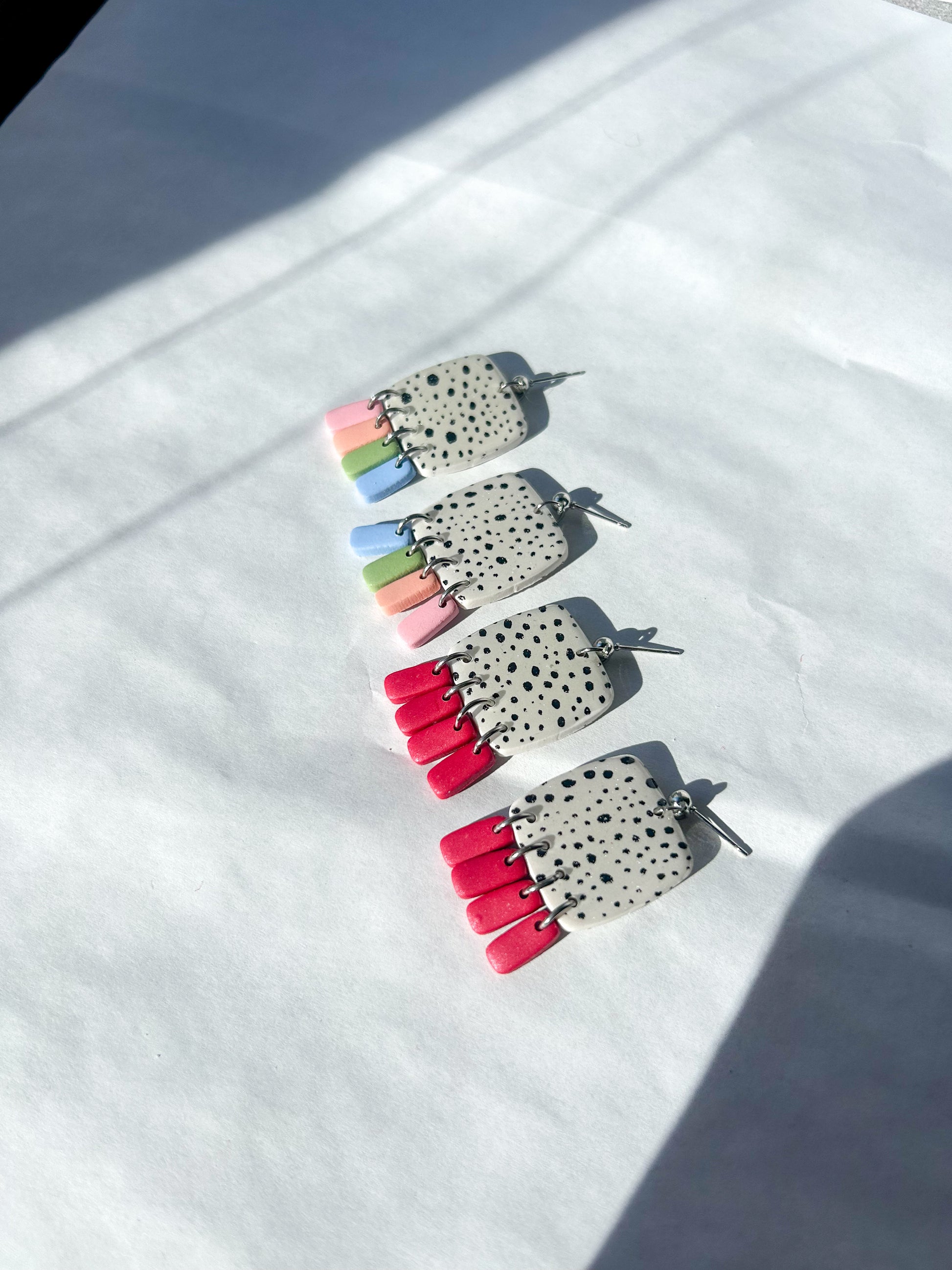 Two pairs of dalmatian patterned earrings laying on a flat surface