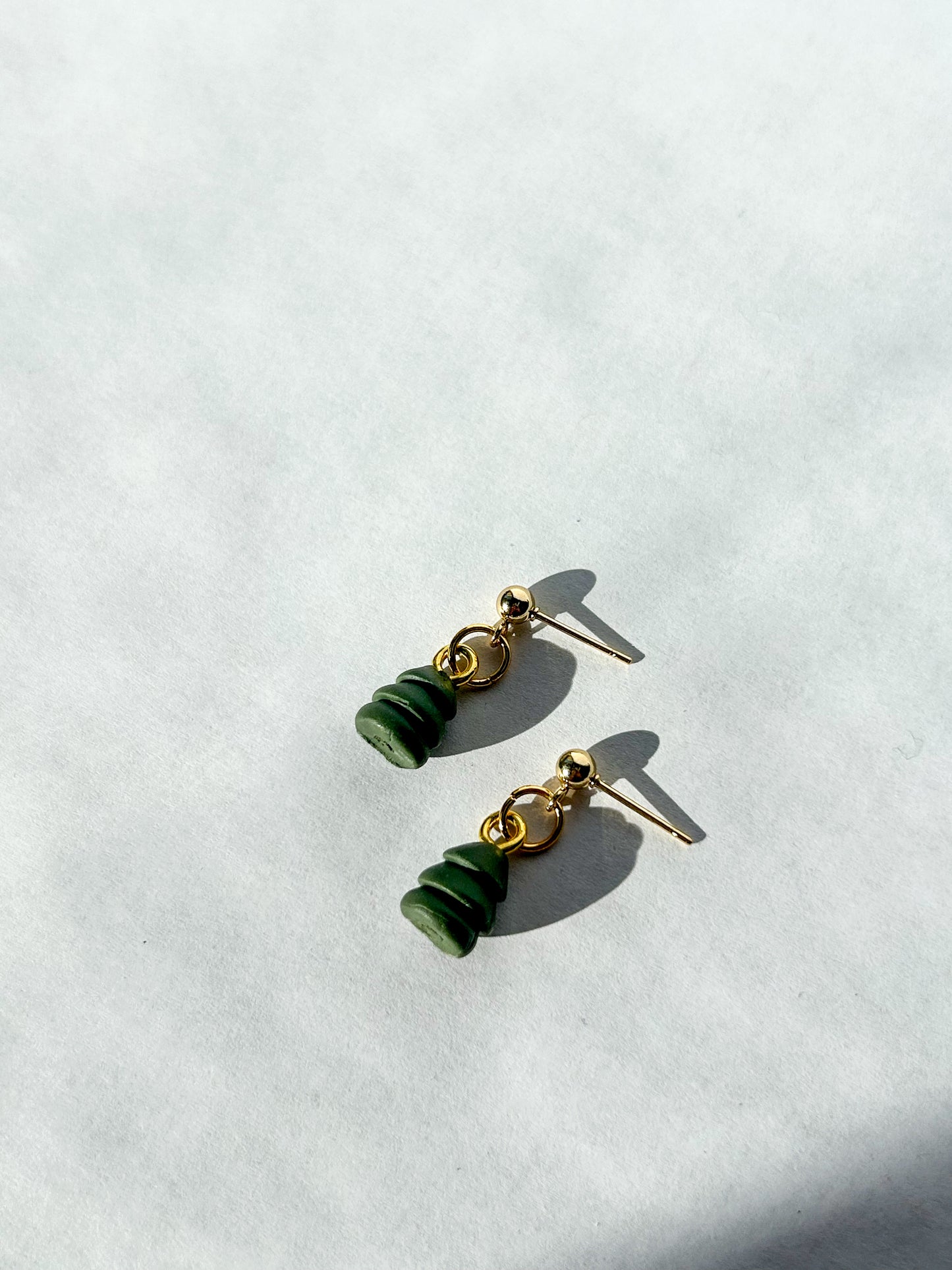 Pair of Christmas tree bead shaped earrings on a white background.