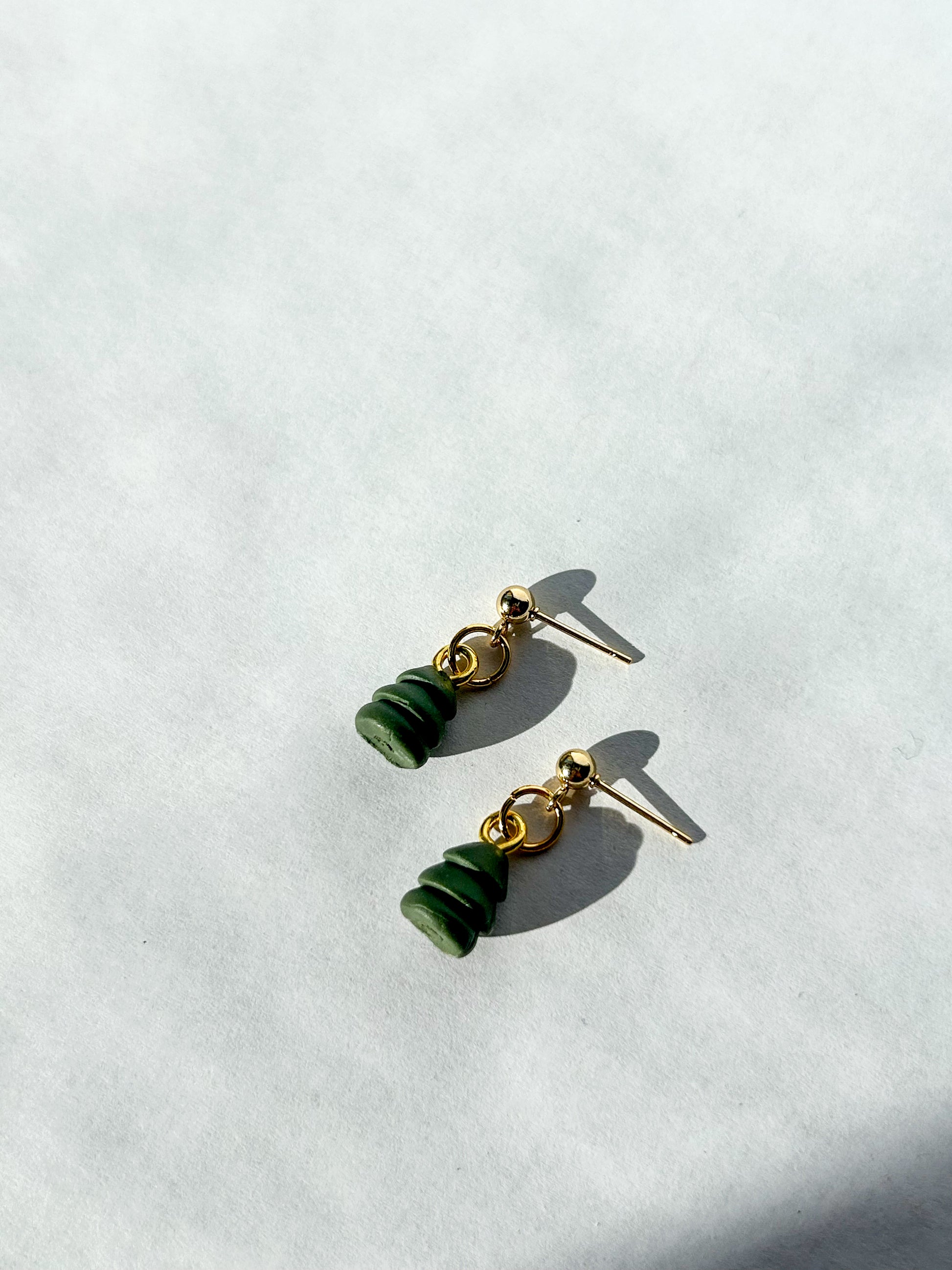 Pair of Christmas tree bead shaped earrings on a white background.