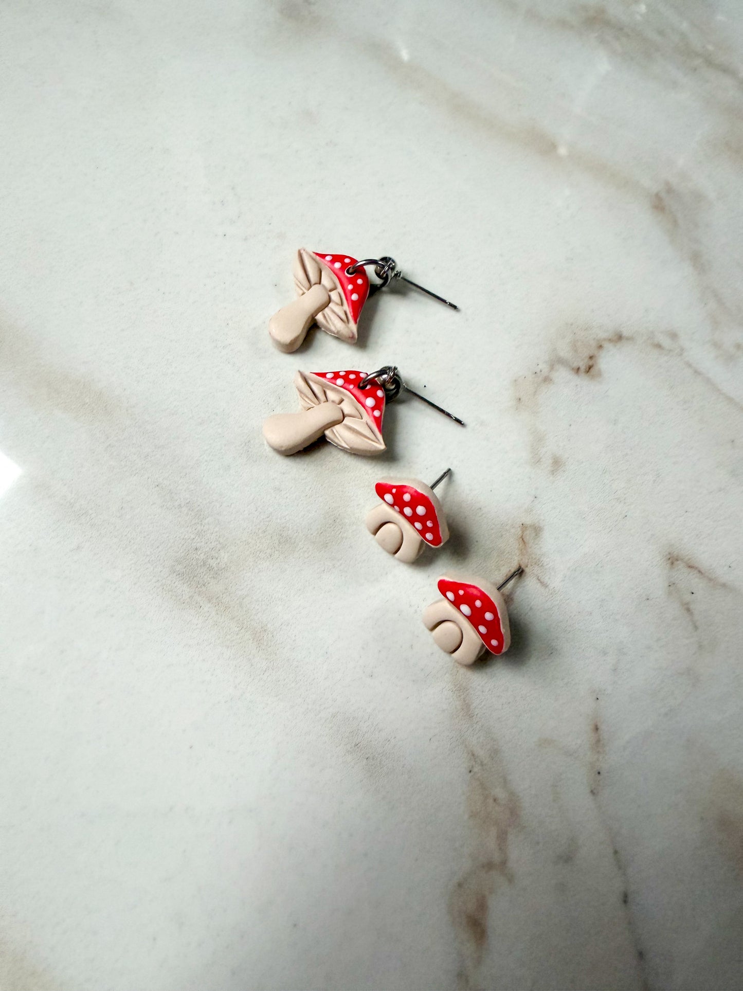 Mushroom-shaped earrings on a marble surface