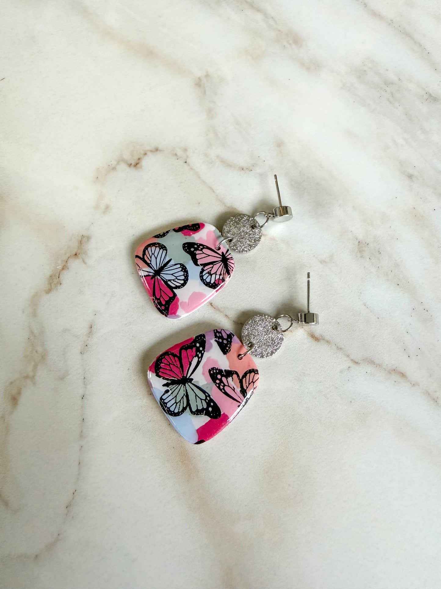 Butterfly patterned earrings on a marble surface