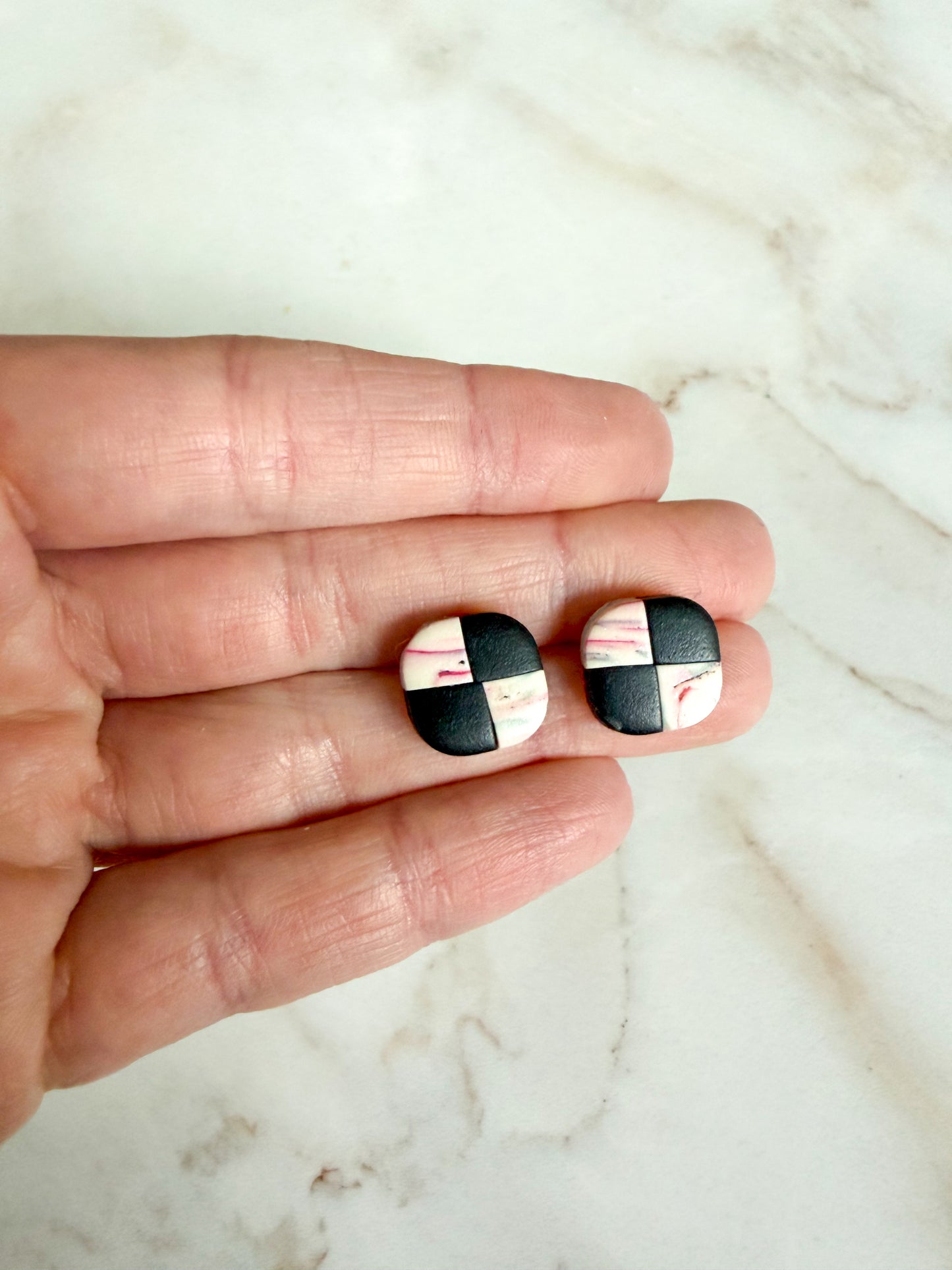 Checker studs held between fingers on a marble surface