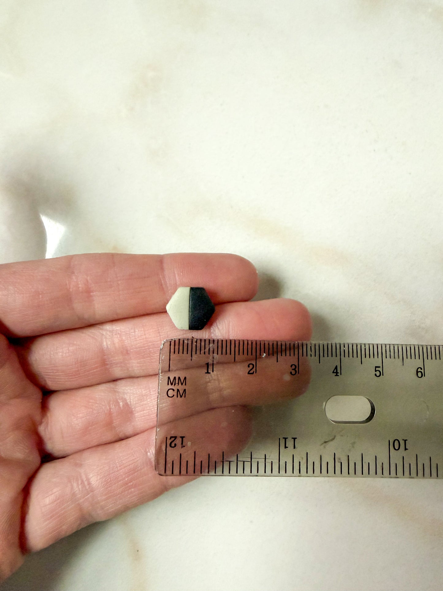 Hexagon studs in front of a ruler for scale. About 1 cm in length