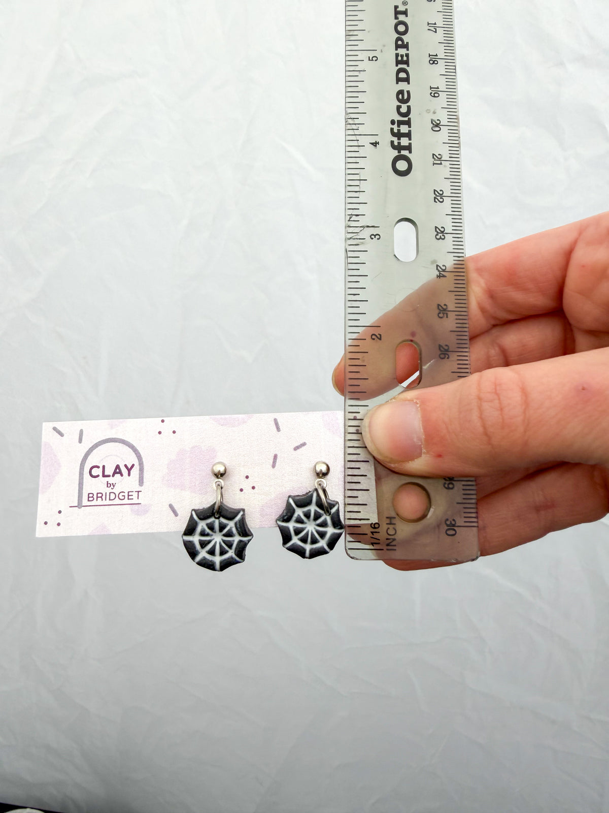Earrings held against a ruler for scale. About .75 inches in length.