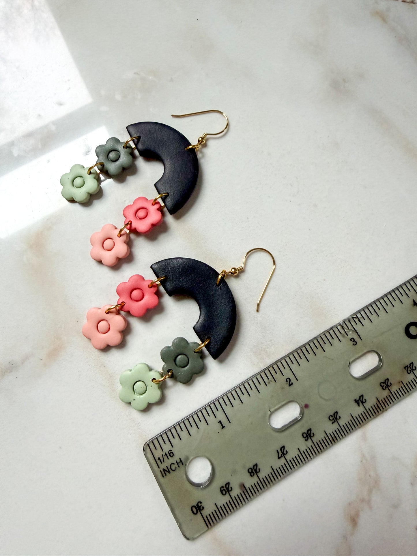 Colorful floral earrings with a ruler for scale on a marble surface. Just under 3 inches in length. 
