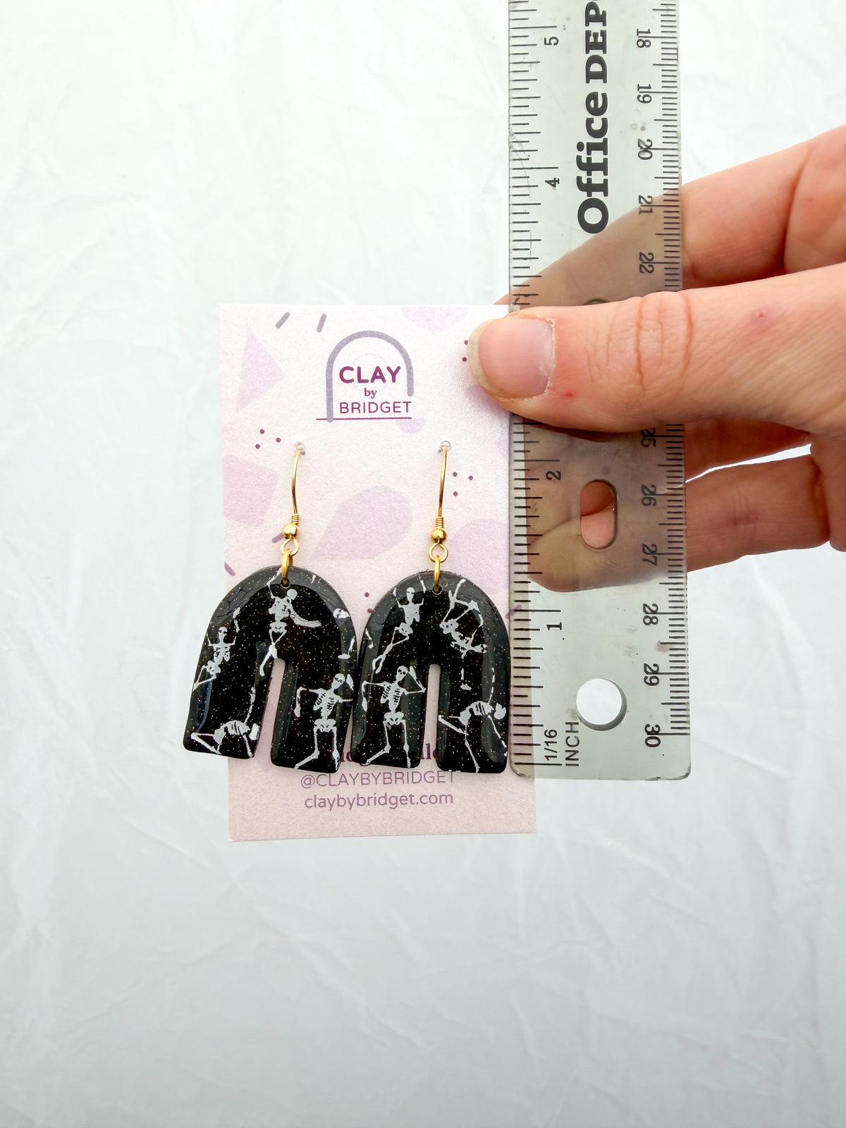 Earrings held against a ruler for scale. About 2 inches in length.