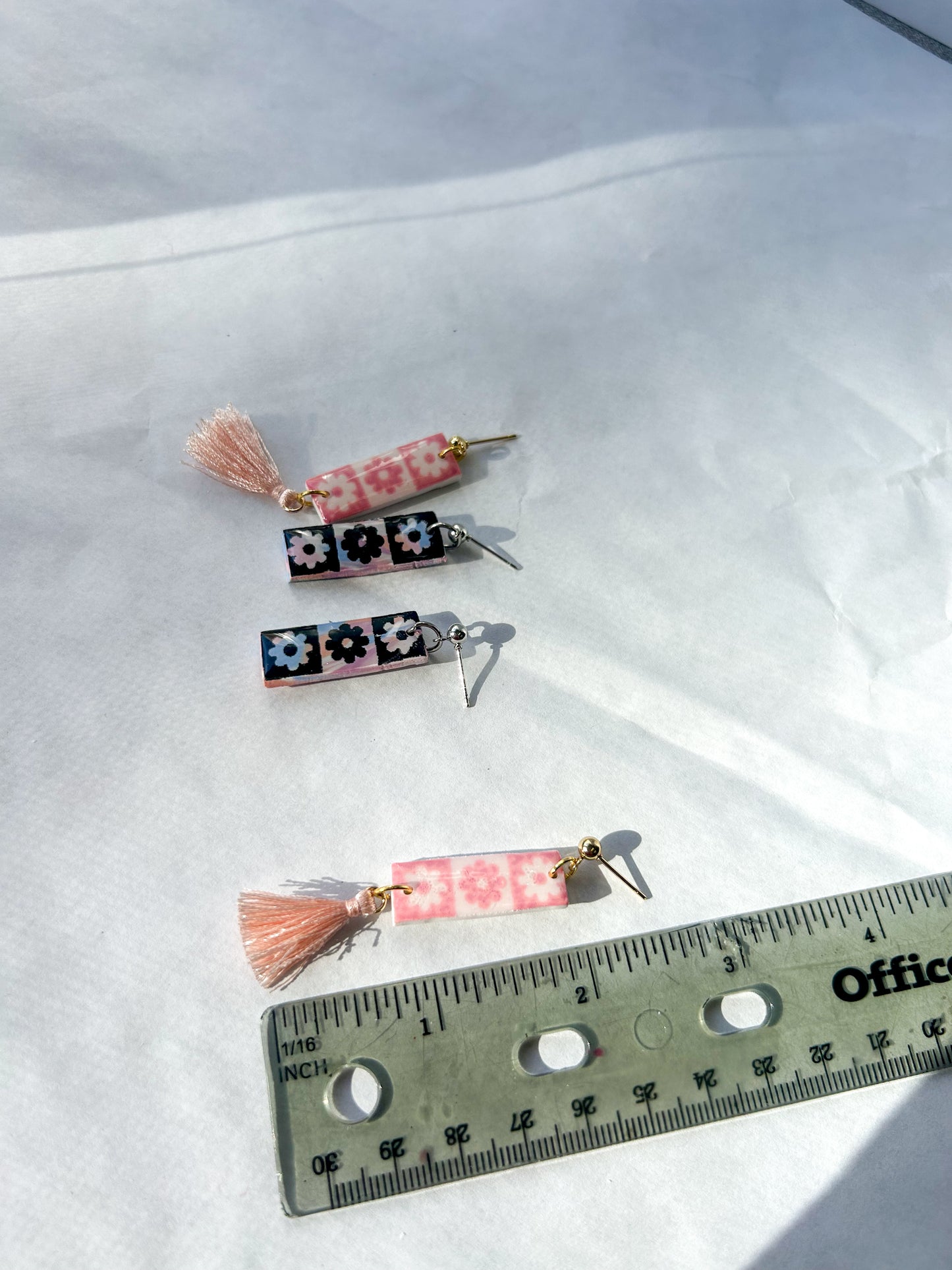 Three decorative earrings  with tassels on a white background, measured against a ruler. 2.5 inches long 