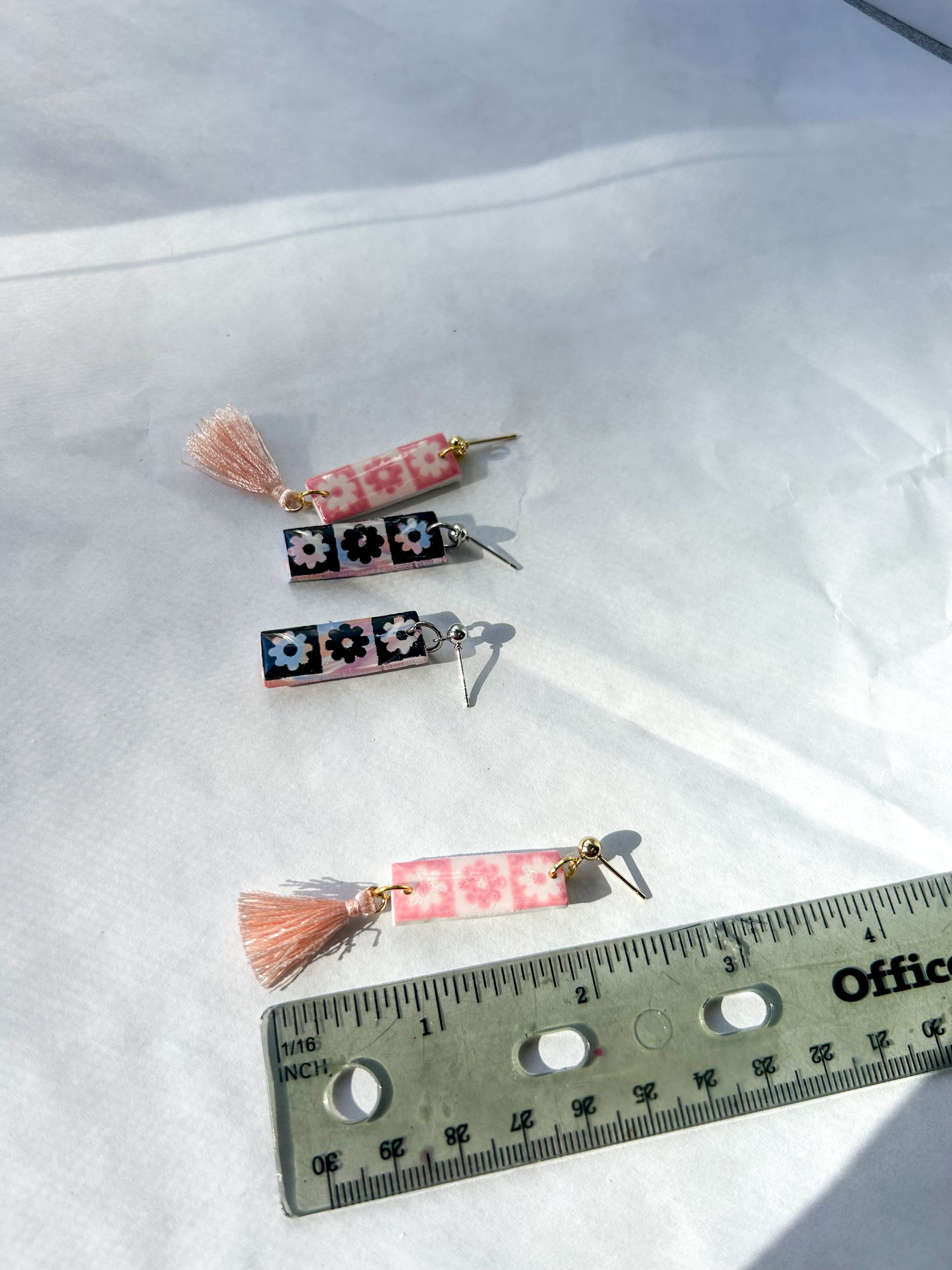 Three decorative earrings  with tassels on a white background, measured against a ruler. 2.5 inches long 