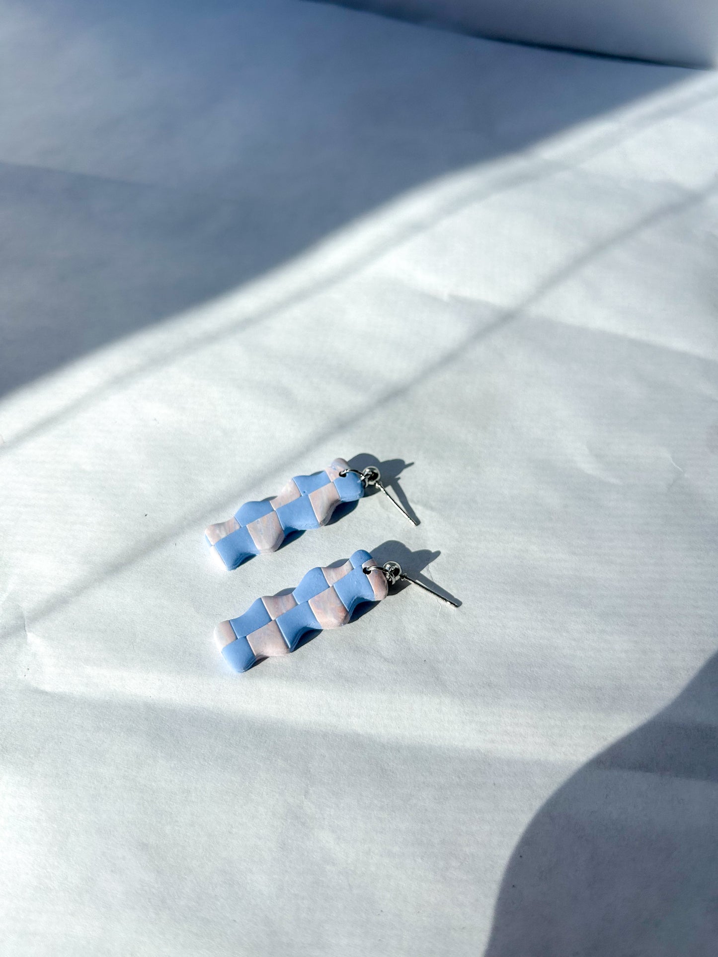 Pair of blue and silver earrings on a white fabric background