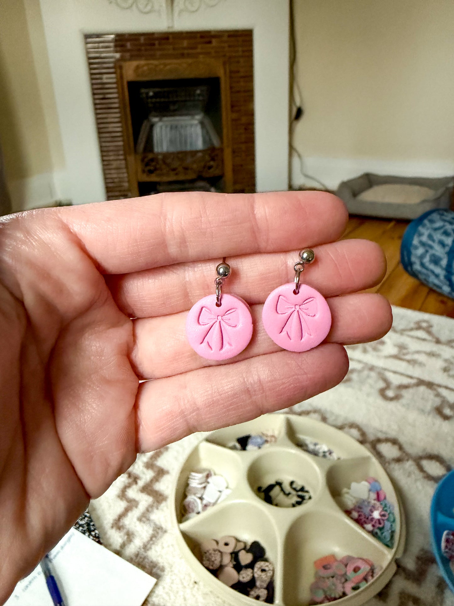 Pink earrings with bow design held in a hand