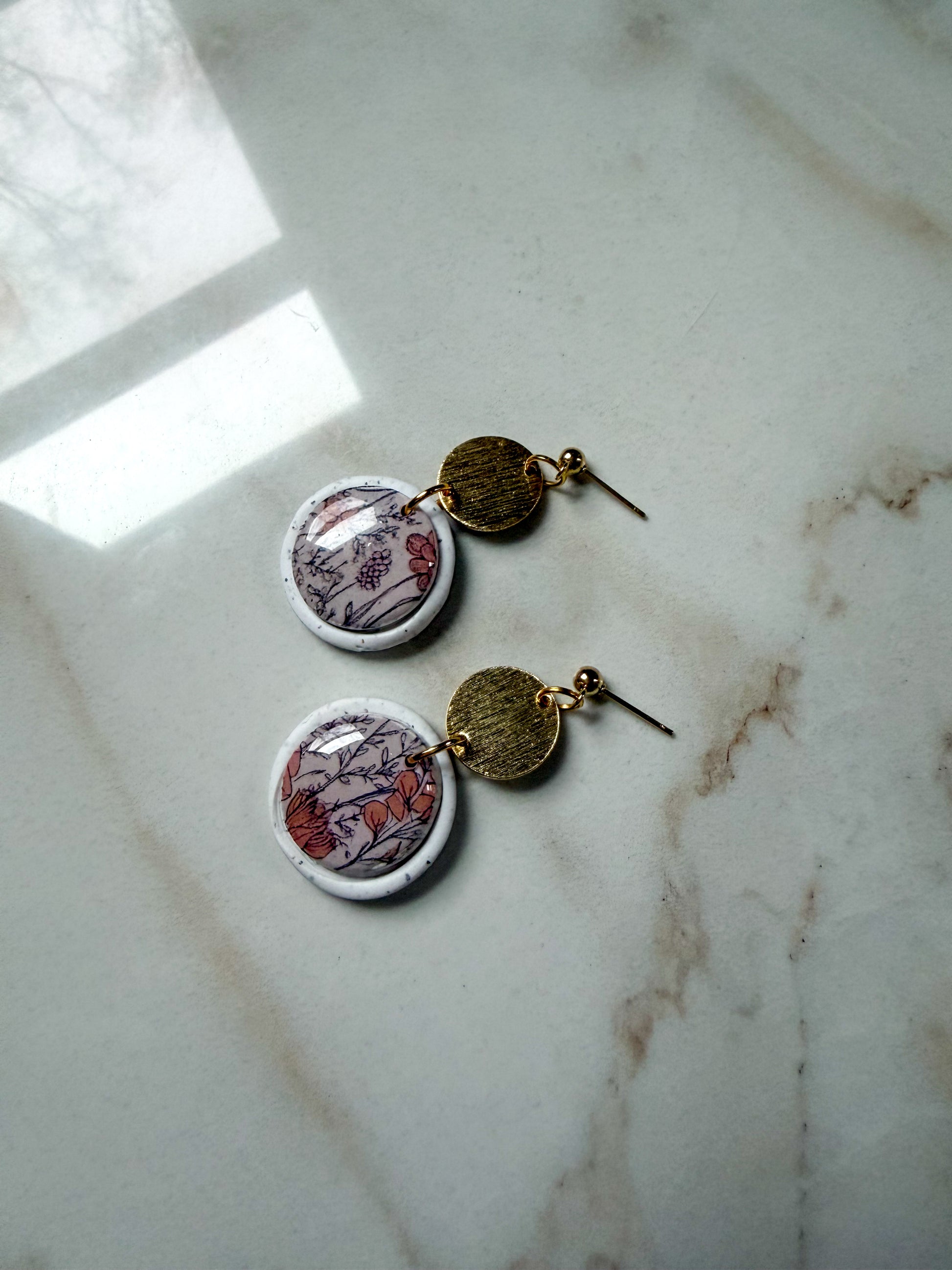 Pair of earrings with circular designs on a marble surface