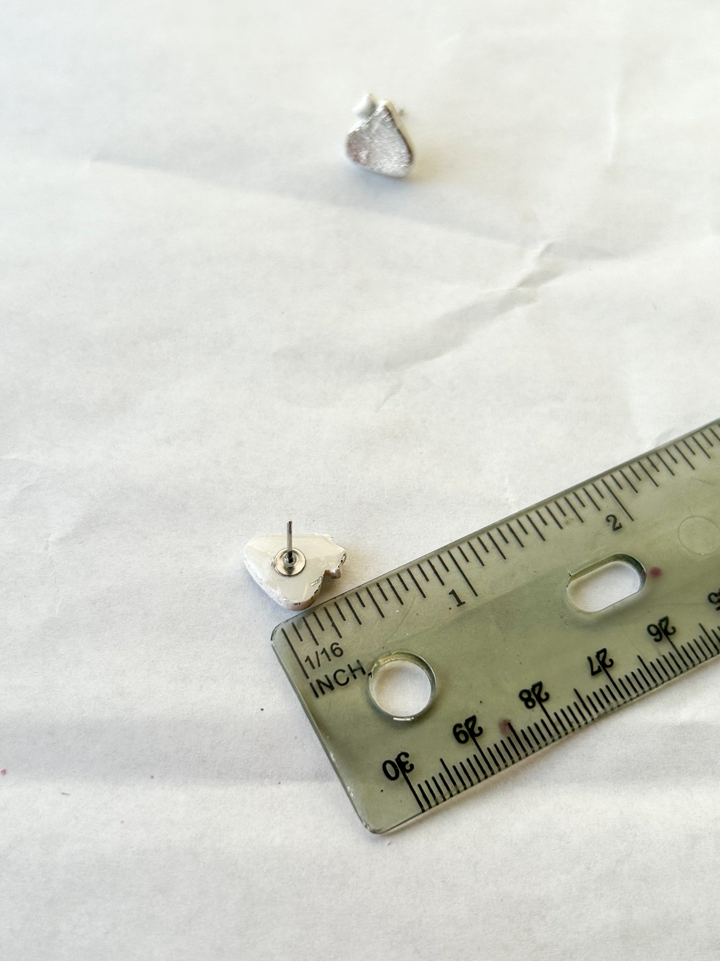 Earrings next to a ruler to show that they are half an inch in length
