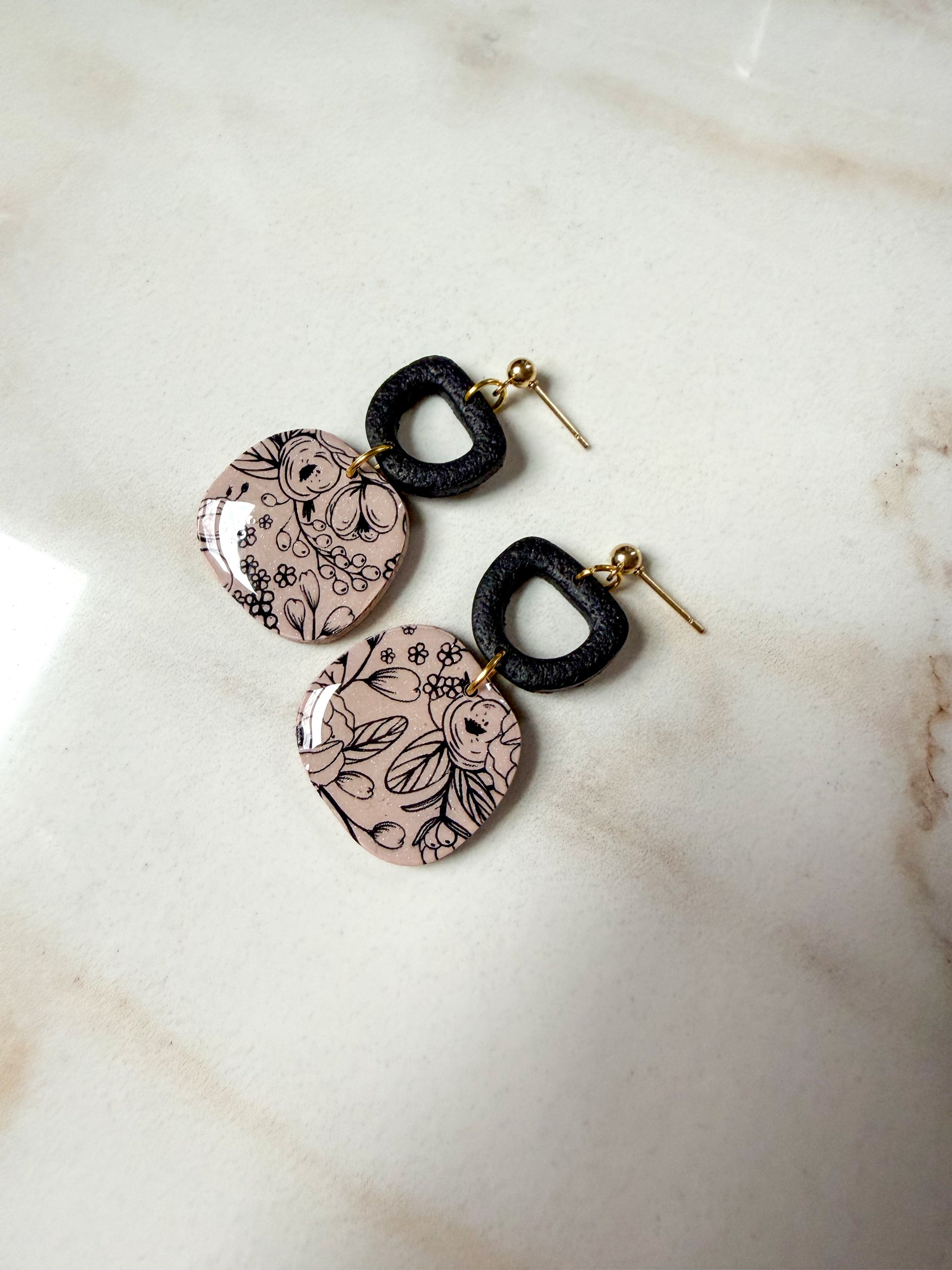 Pair of earrings with floral patterns on a marble surface