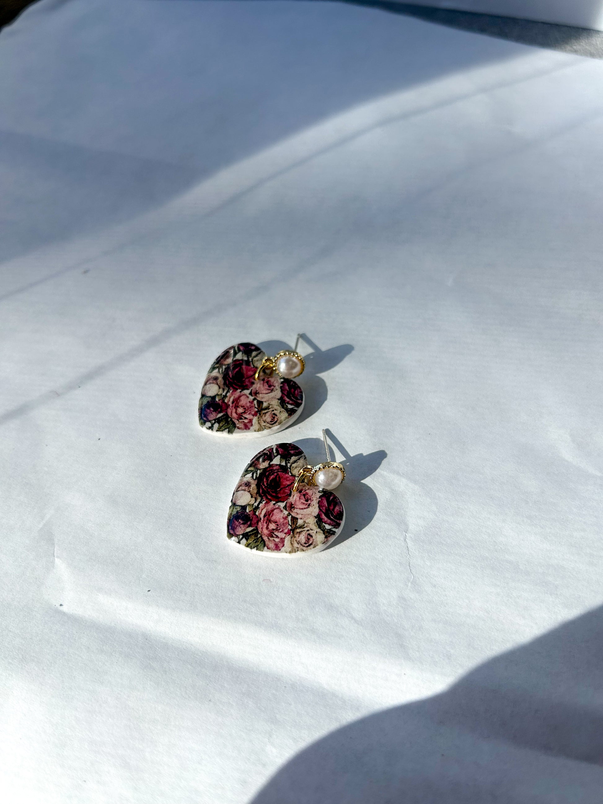 Heart-shaped floral earrings on a white surface