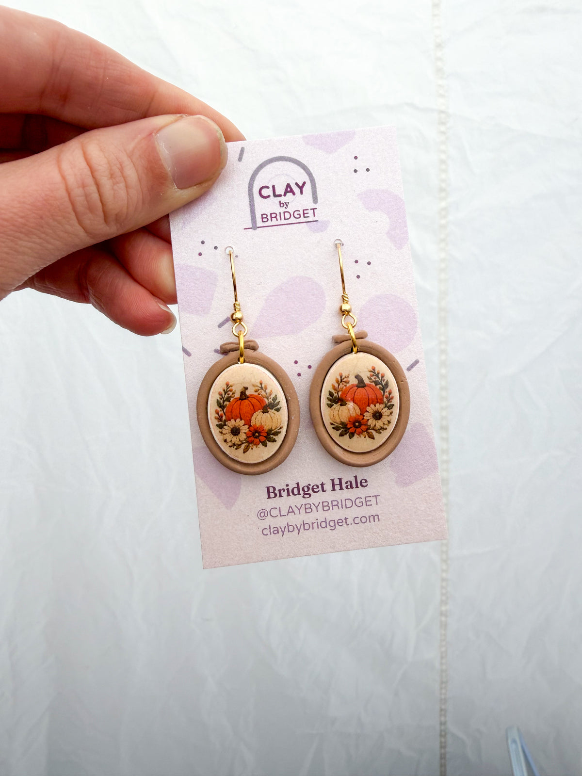 Embroidery hoop shaped earrings with a fall pumpkin design inside.