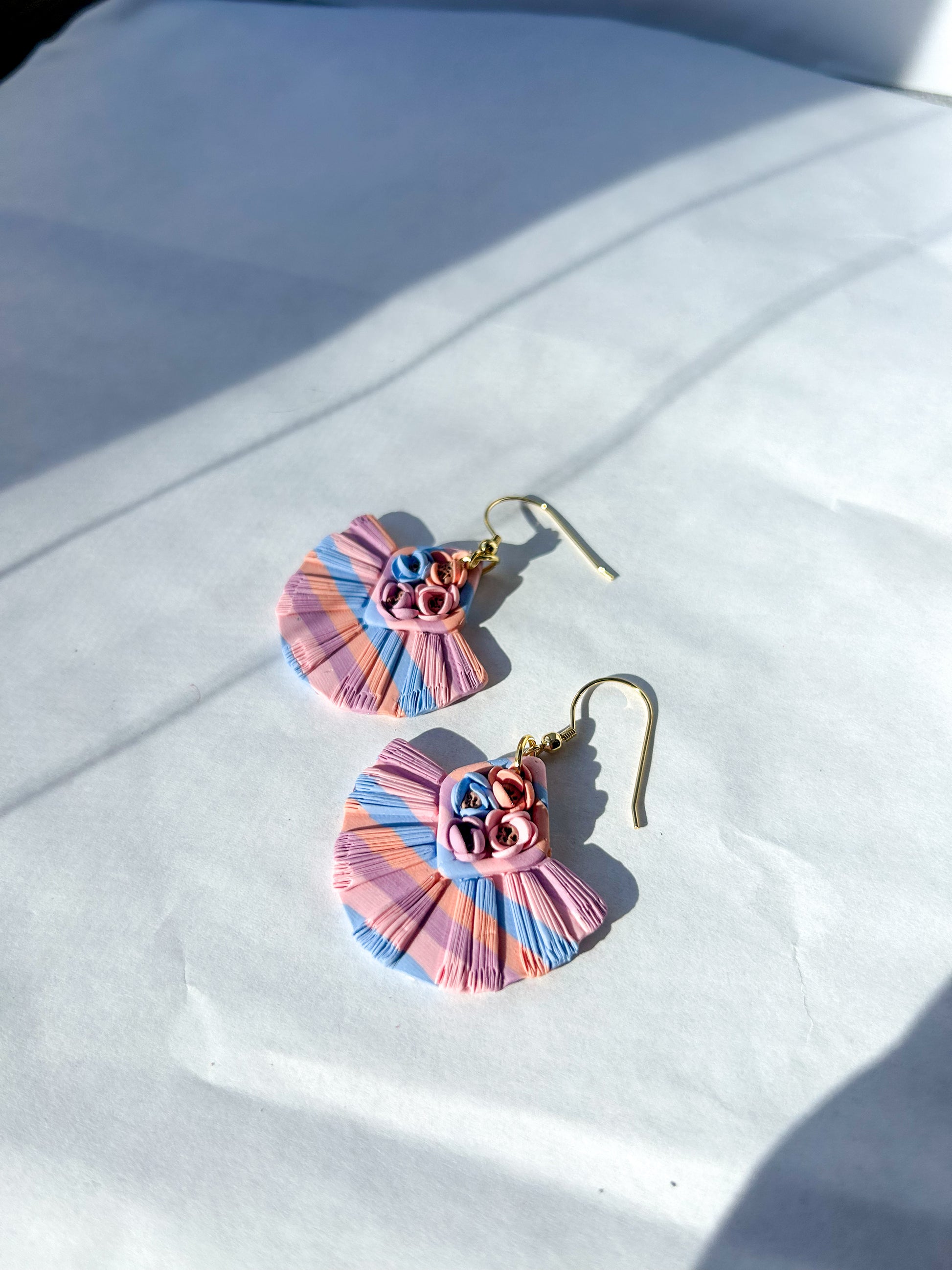 Pair of colorful ruffled earrings on a white fabric background