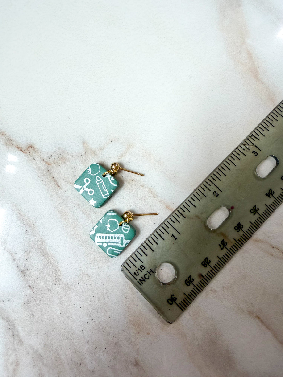 Earrings next to a ruler for scale. A little over 1/2 inch long. 