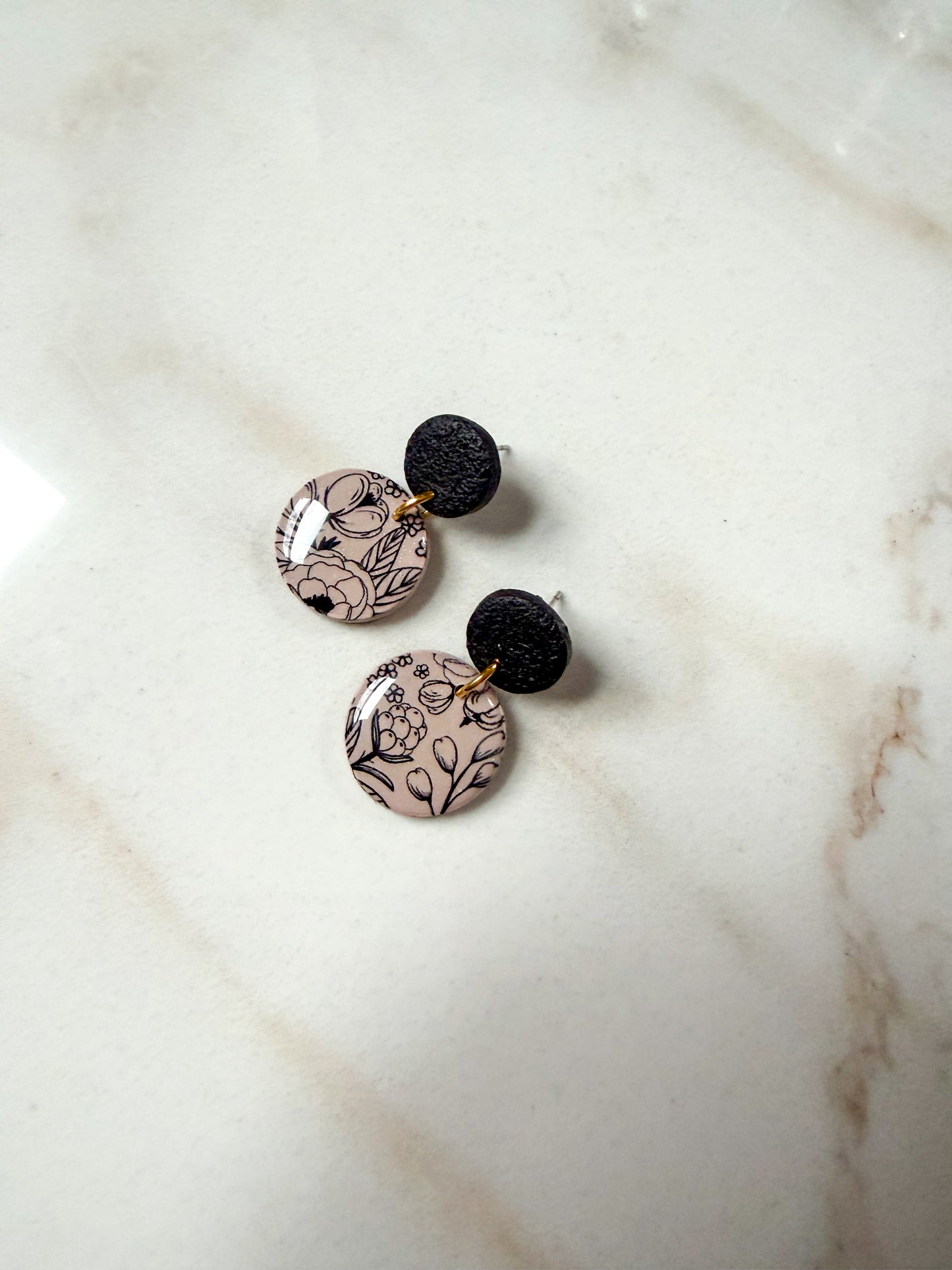 Floral patterned circle dangles on a marble surface 