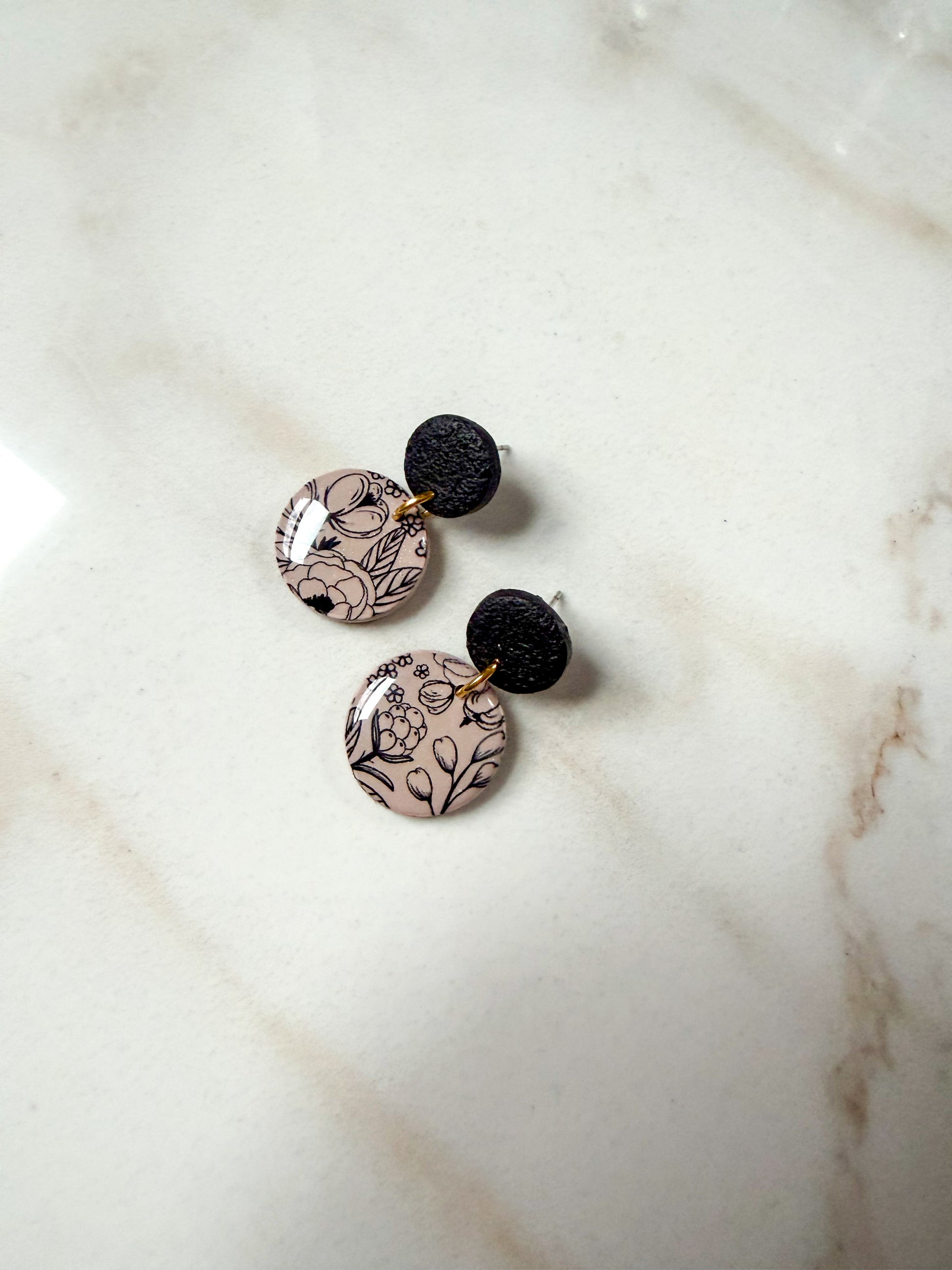 Floral patterned circle dangles on a marble surface 