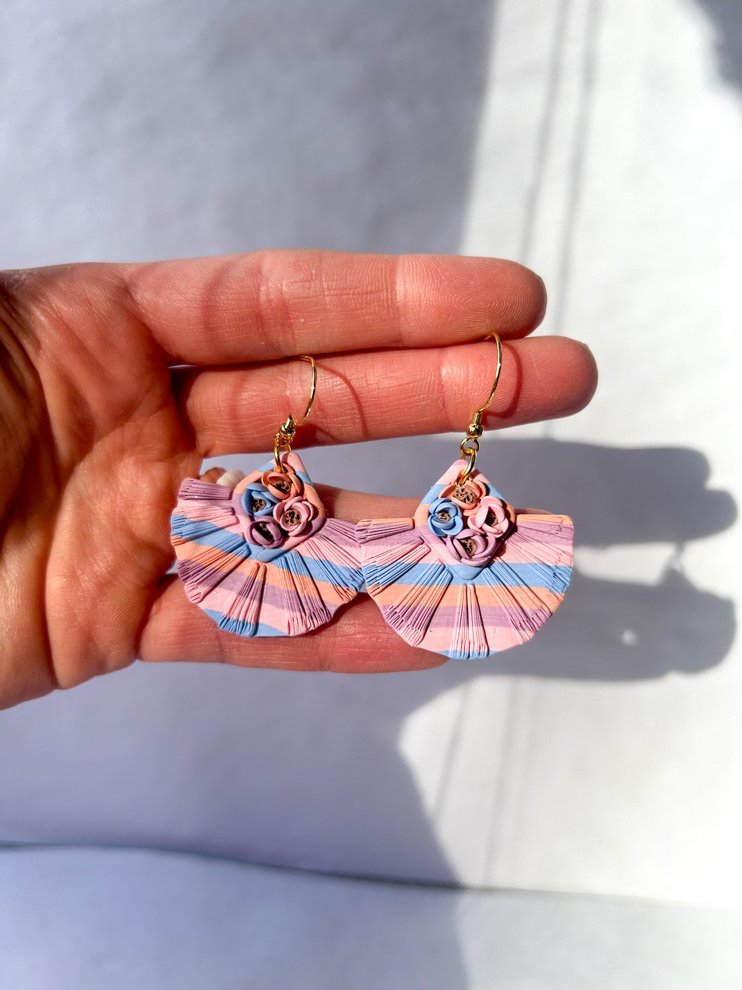 Hand holding a pair of colorful earrings with a light background