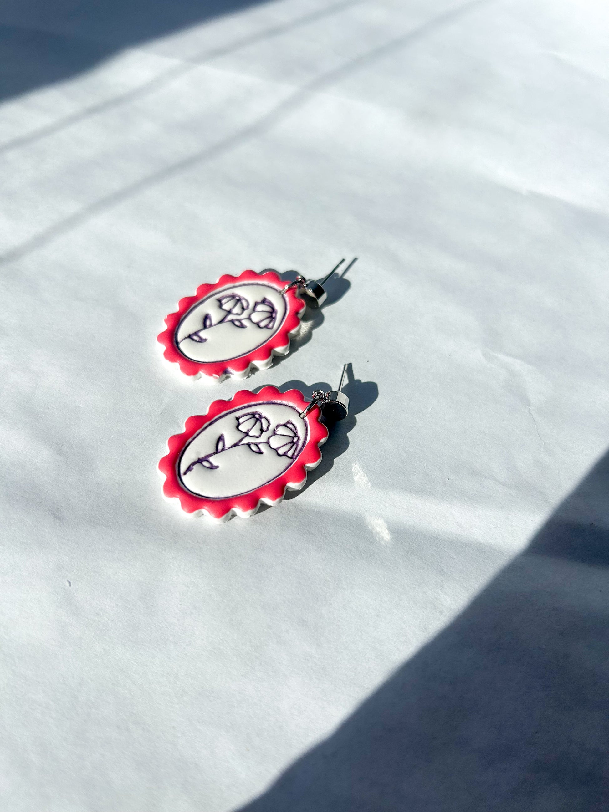 Red and white earrings with floral design on a white surface